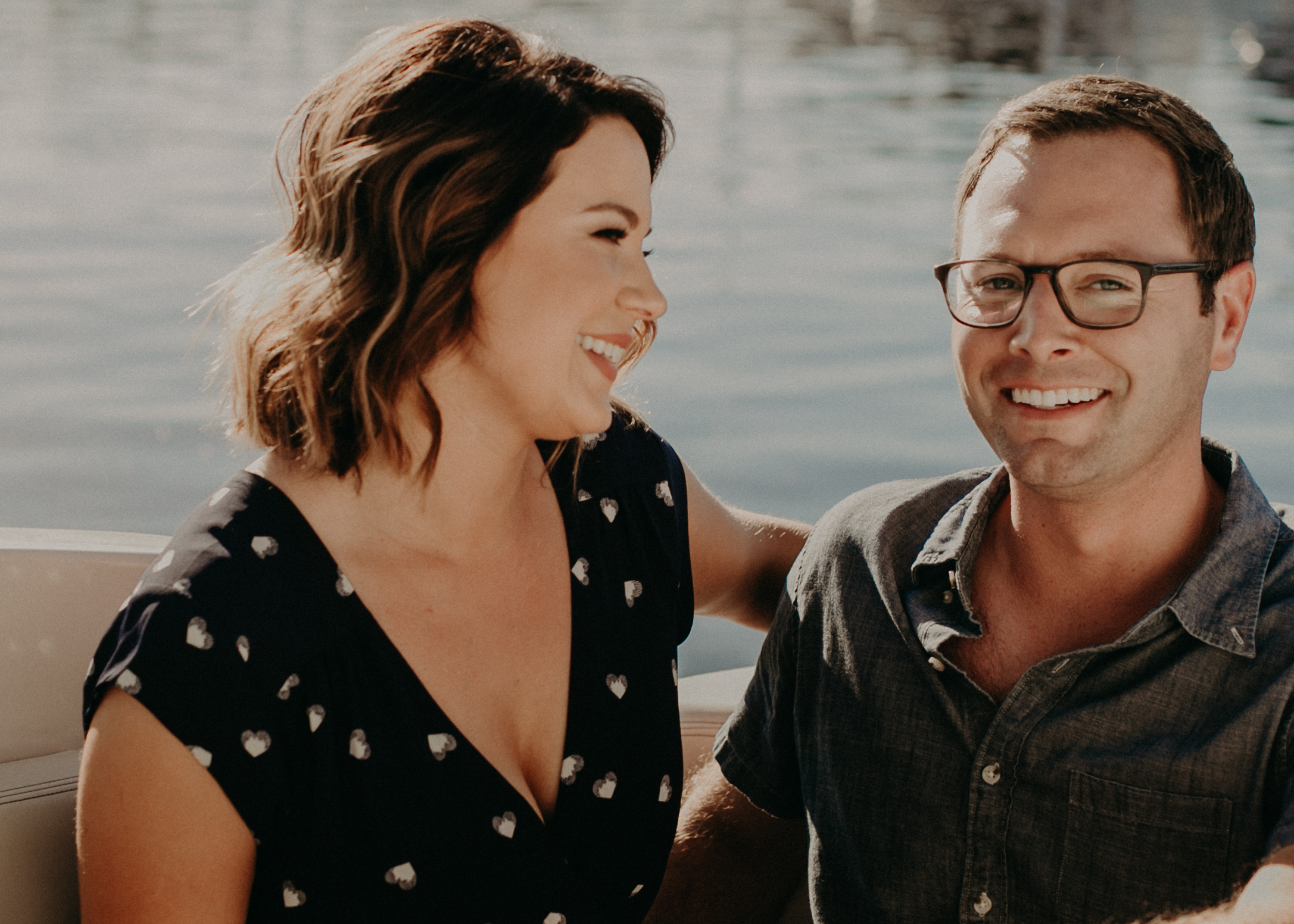 a beautiful and happy couple smiles at the camera during their engagement session on their boat in the St Croix Marina