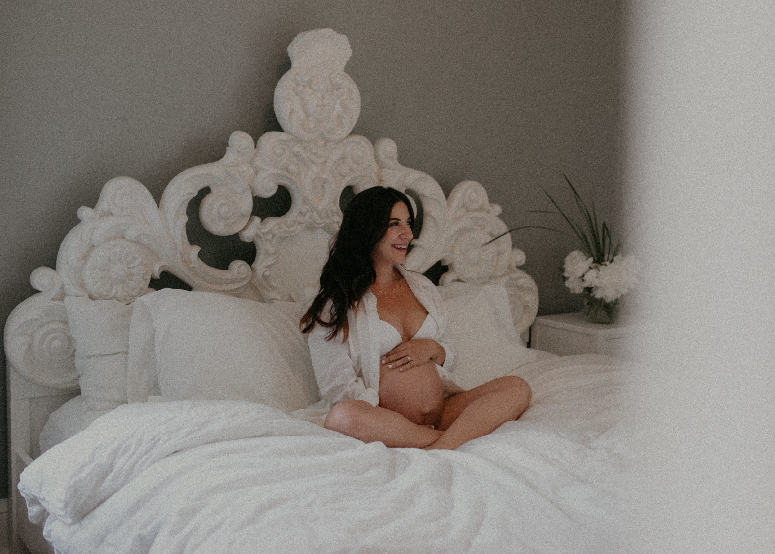  Minneapolis blogger sits on her bed in her husband’s white shirt and white bra and panties during an intimate maternity session 