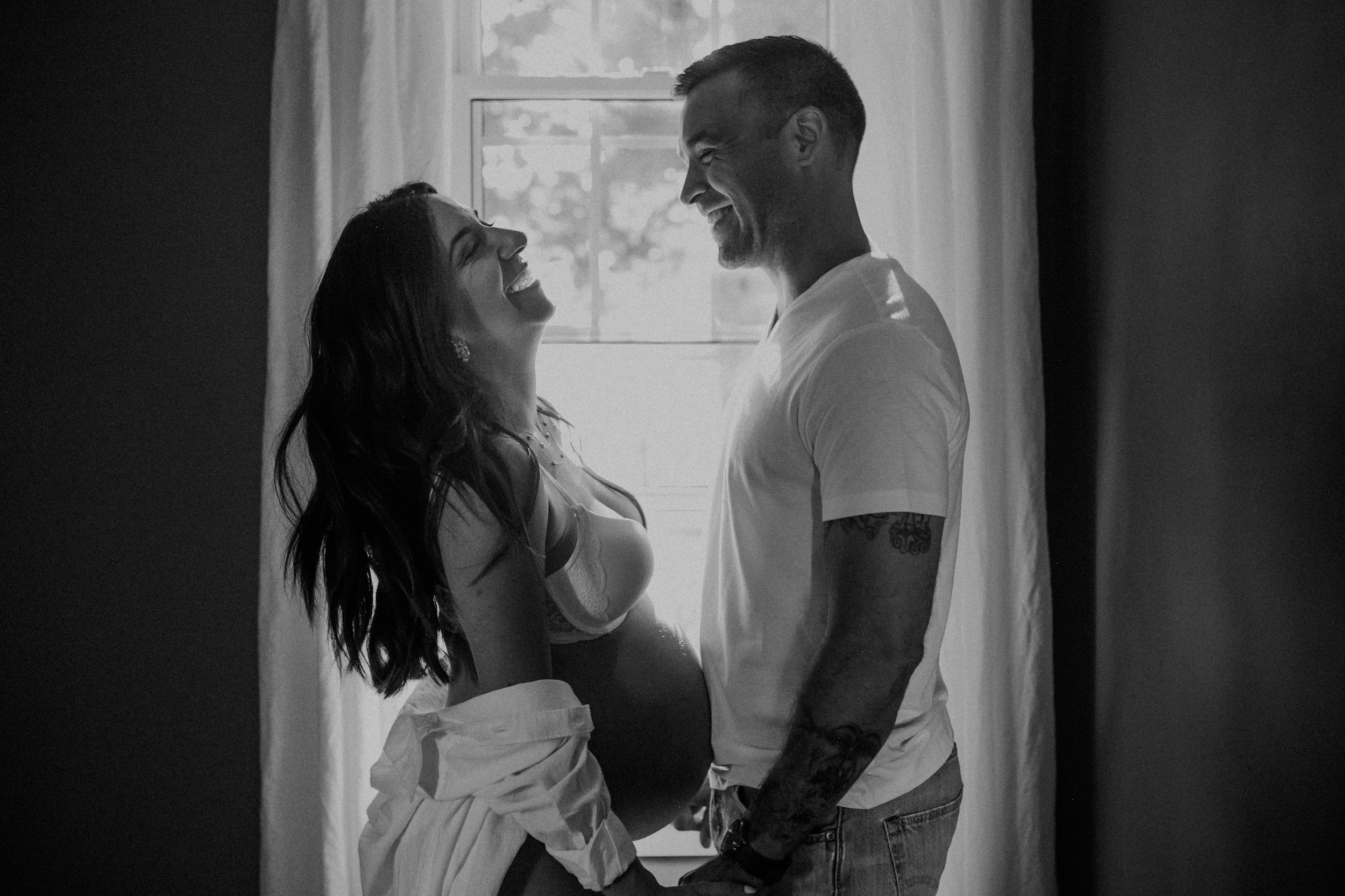 a cozy and intimate black and white image of woman pregnant with her partner during maternity photos