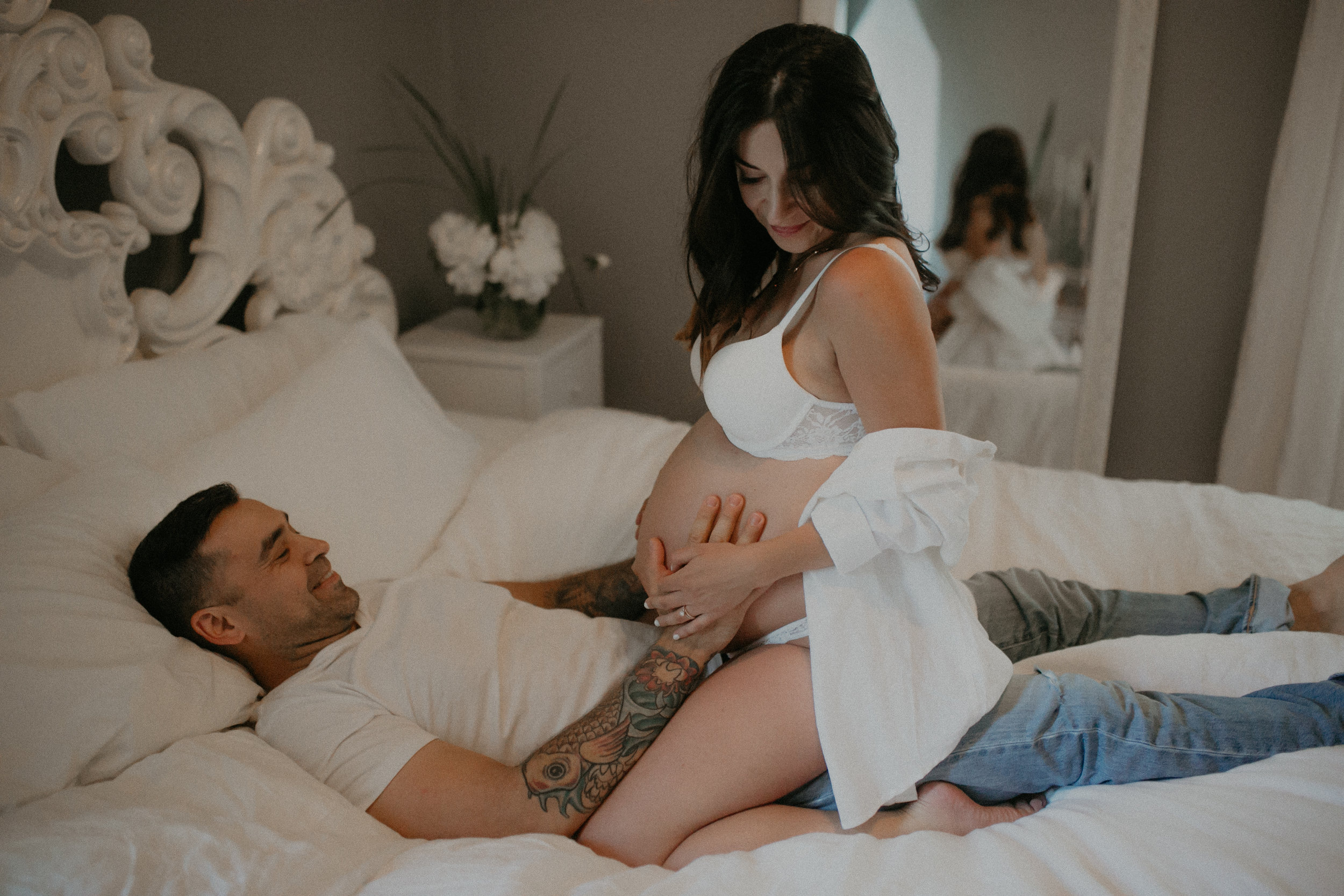 a sexy Minneapolis couple and blogger plays on the bed during intimate maternity session with Andrea Wagner