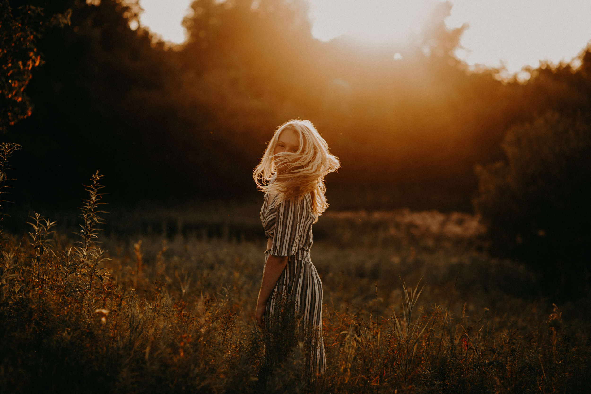 incredible sunset with golden light in a field while high school senior from Spooner WI whips her hair to look at photography Andrea Wagner