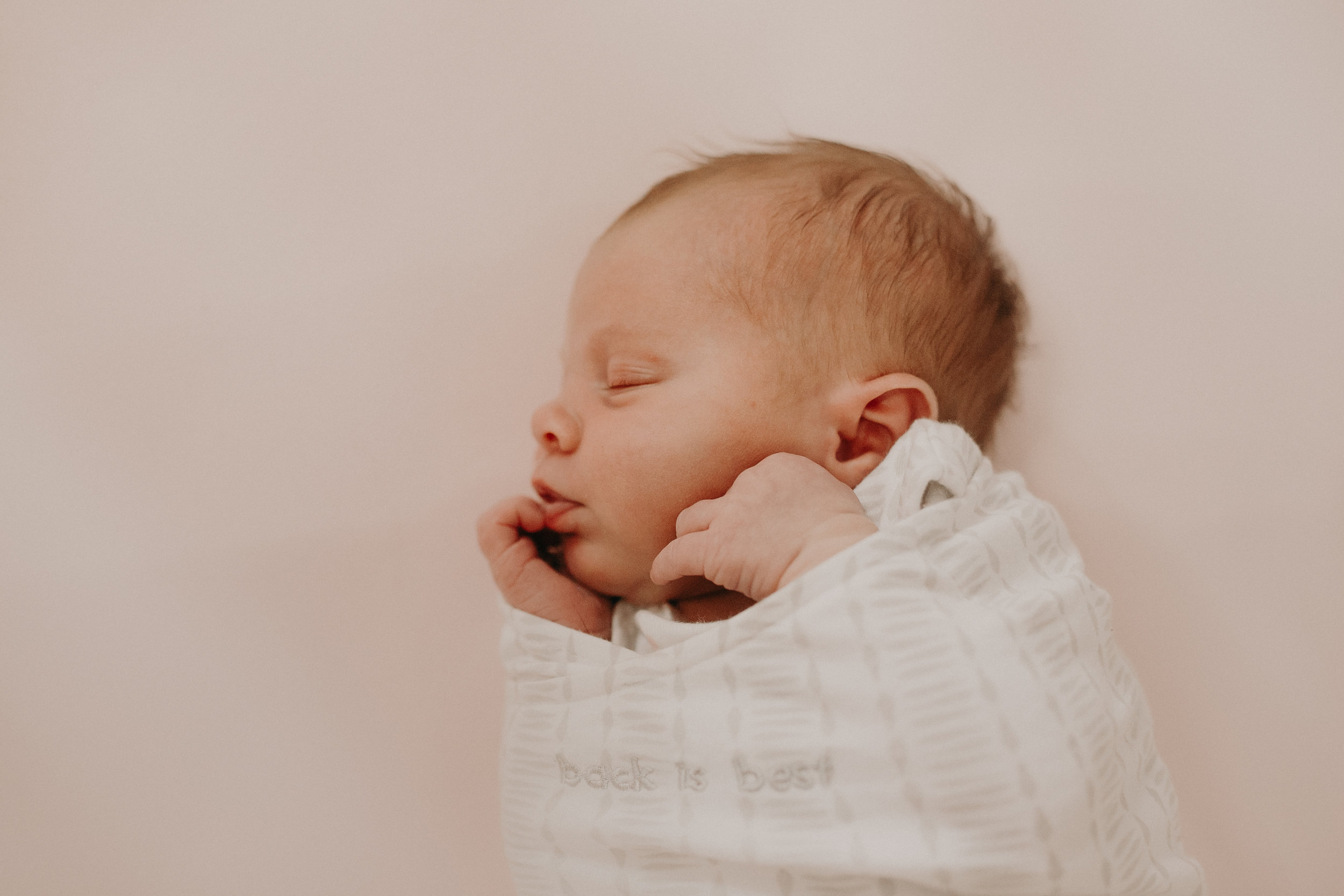  newborn lifestyle photographer Andrea Wagner captures cute baby wrapped up in her crib 