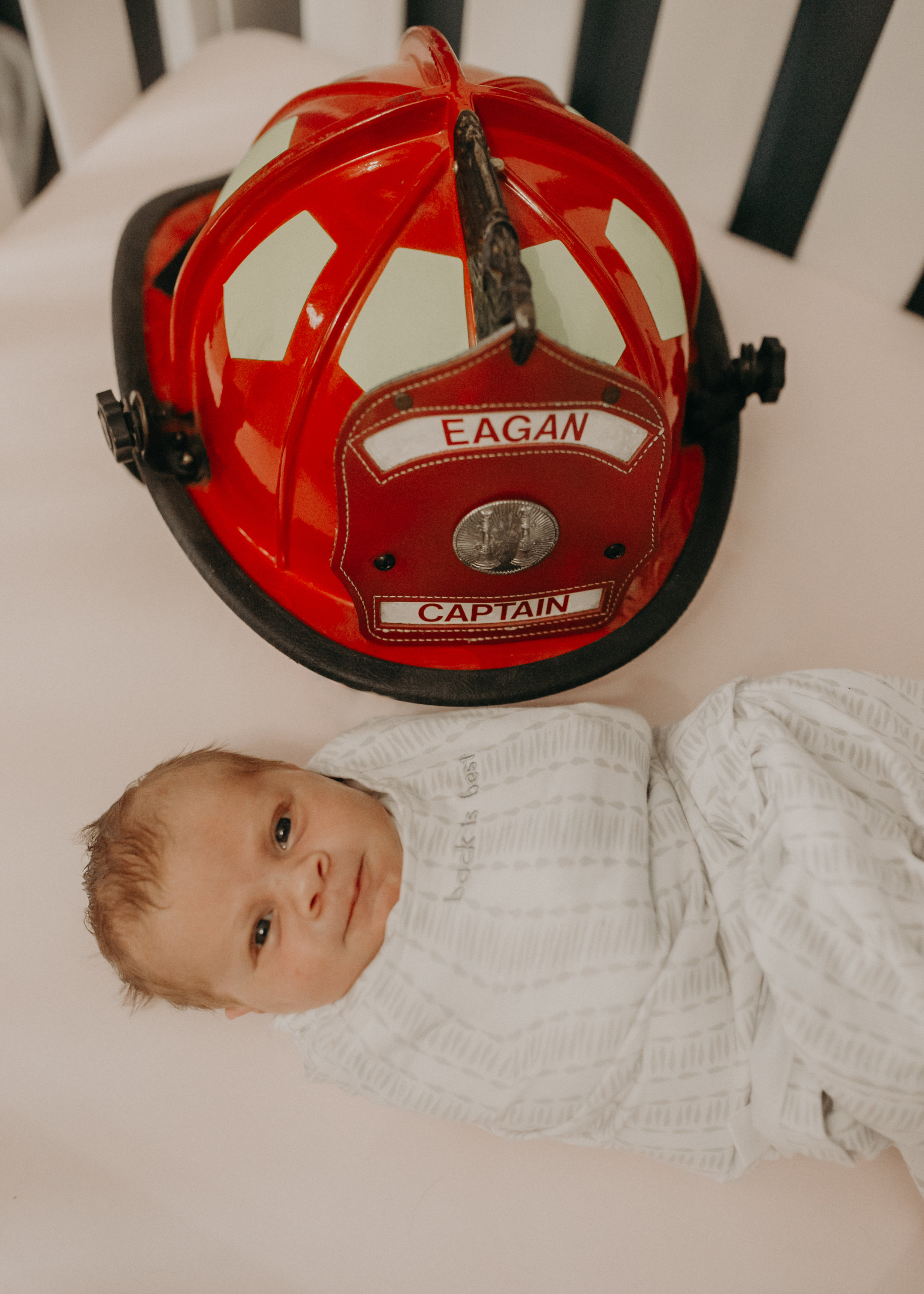  newborn baby poses by firefighter helmet in Eagan MN during newborn photo session 