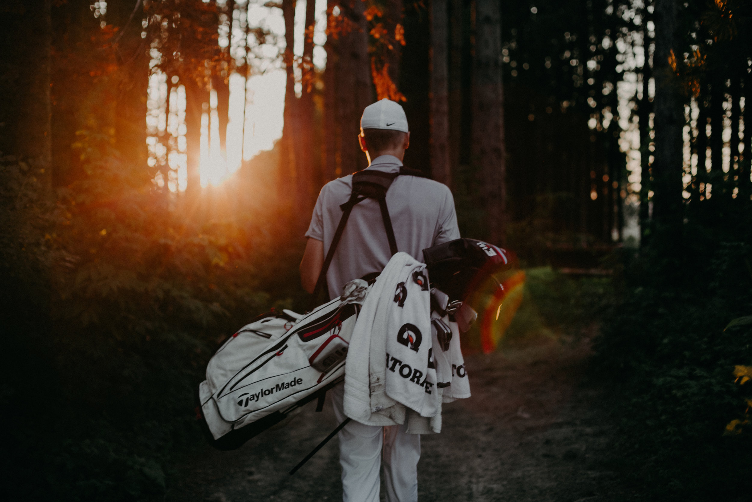 golfer carrying his clubs during sunset photo session at Spring Valley Golf Club in Wisconsin