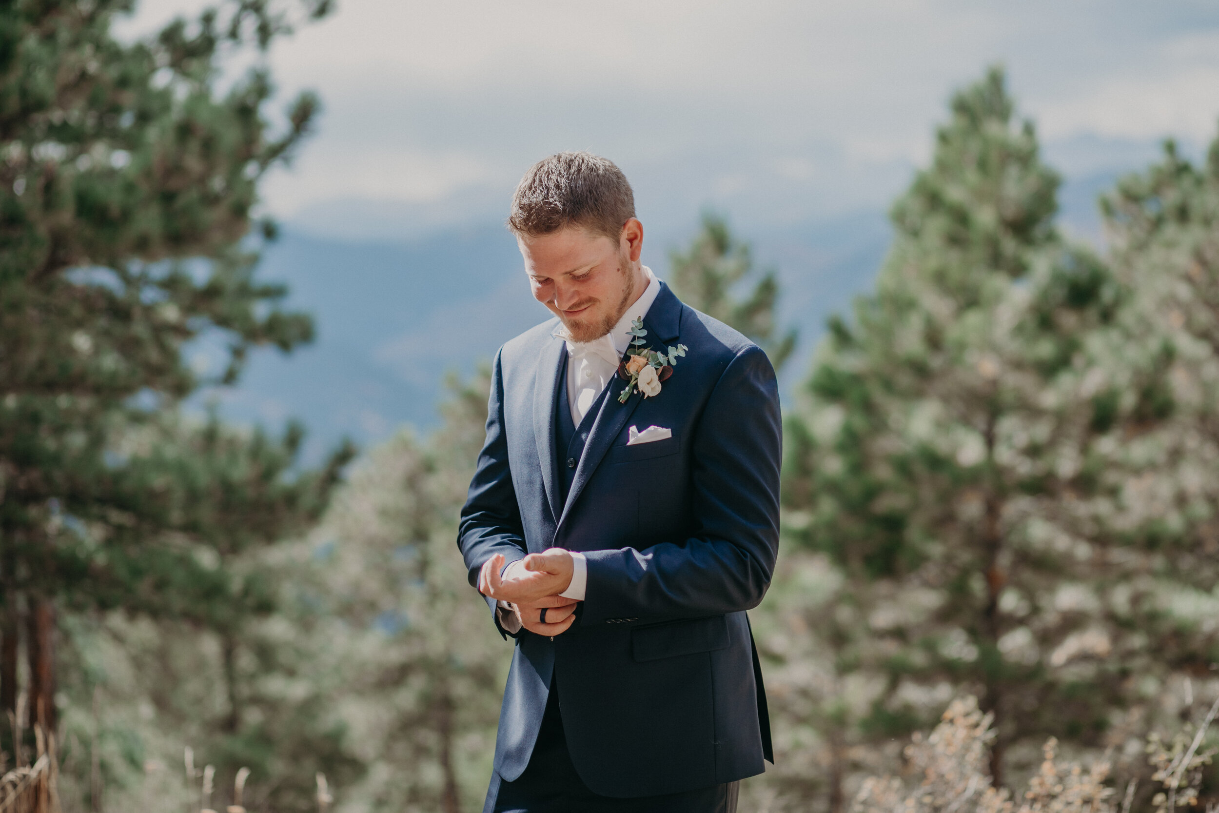  a groom prepares to see his bride during a first look on Flagstaff Mountain 