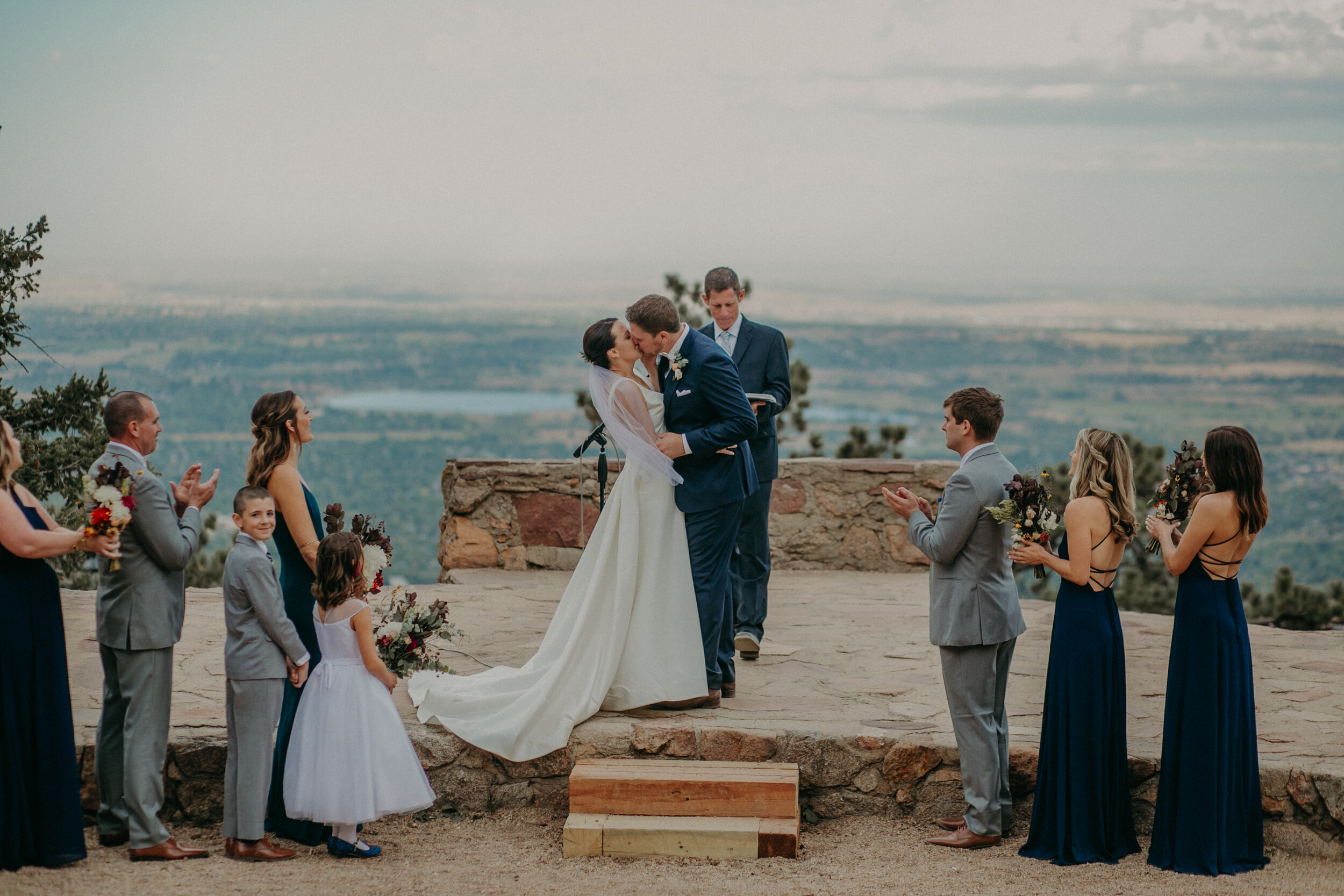  a groom kisses his wife during their wedding ceremony at Sunrise Amphitheater on Flagstaff Mountain in Colorado 