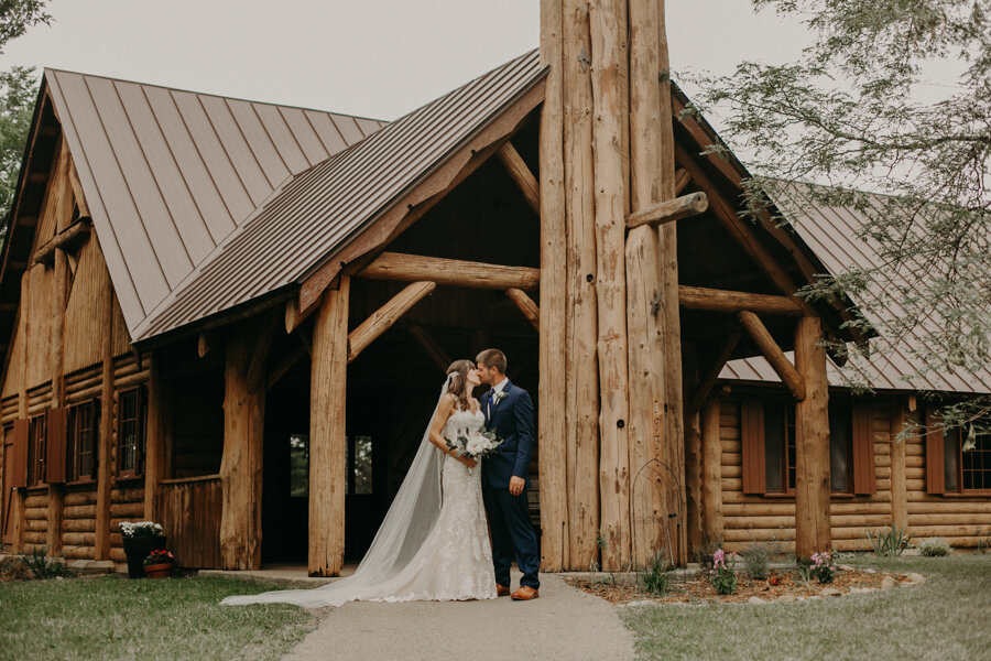 bride and groom pose in front of the chapel at Pine Lake Resort in Waupaca WI