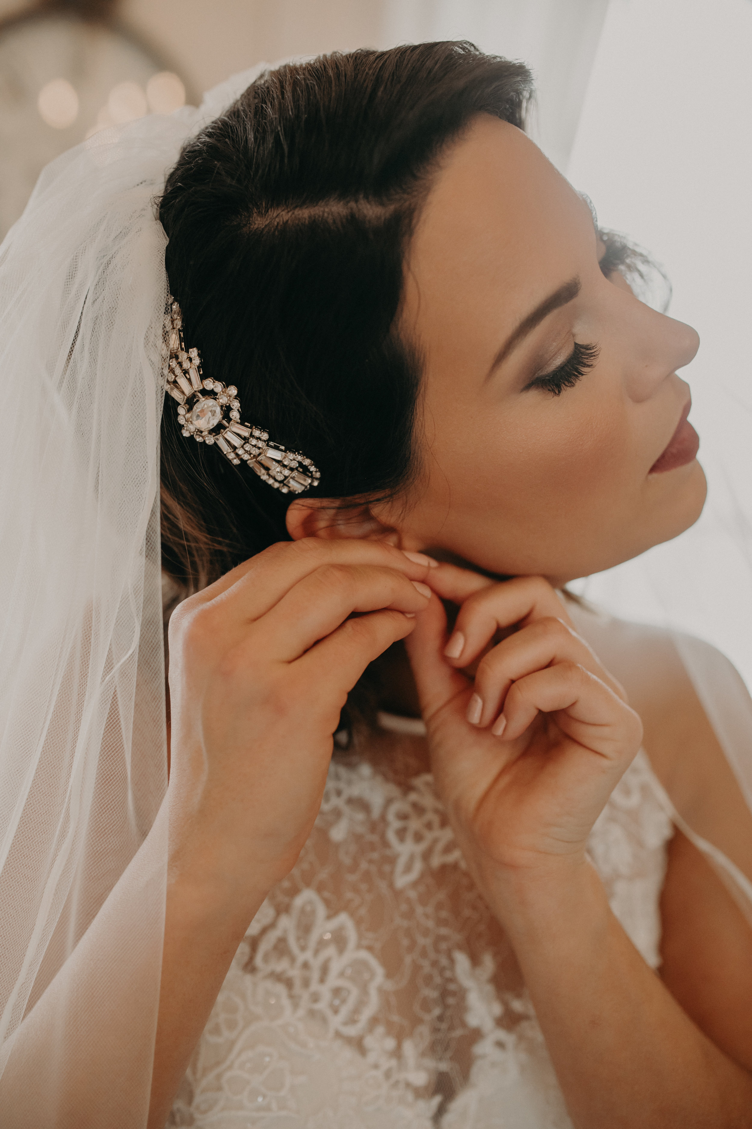 a bride puts on her earrings before her wedding in the getting ready space at The Loft at Studio J