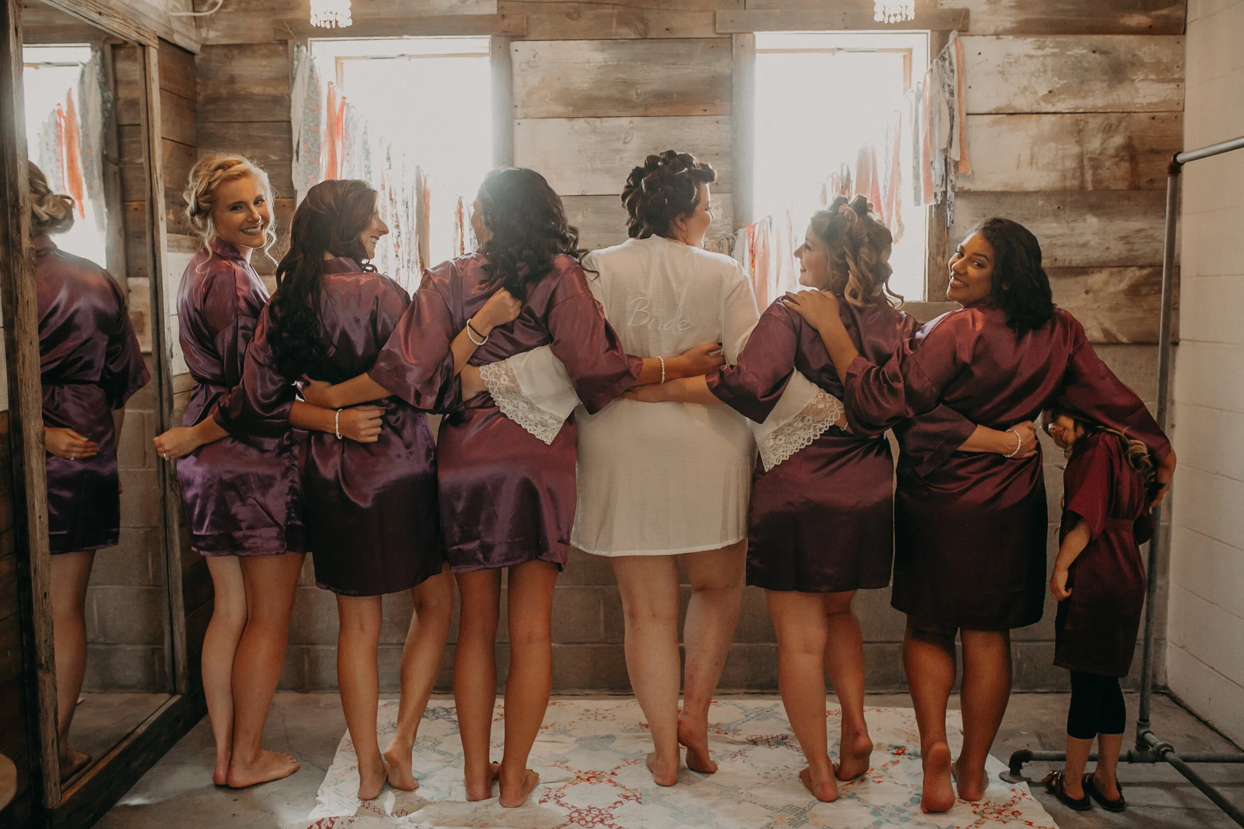 bridesmaids pose with the bride at The Mumm Barn for a wedding in Clayton WI