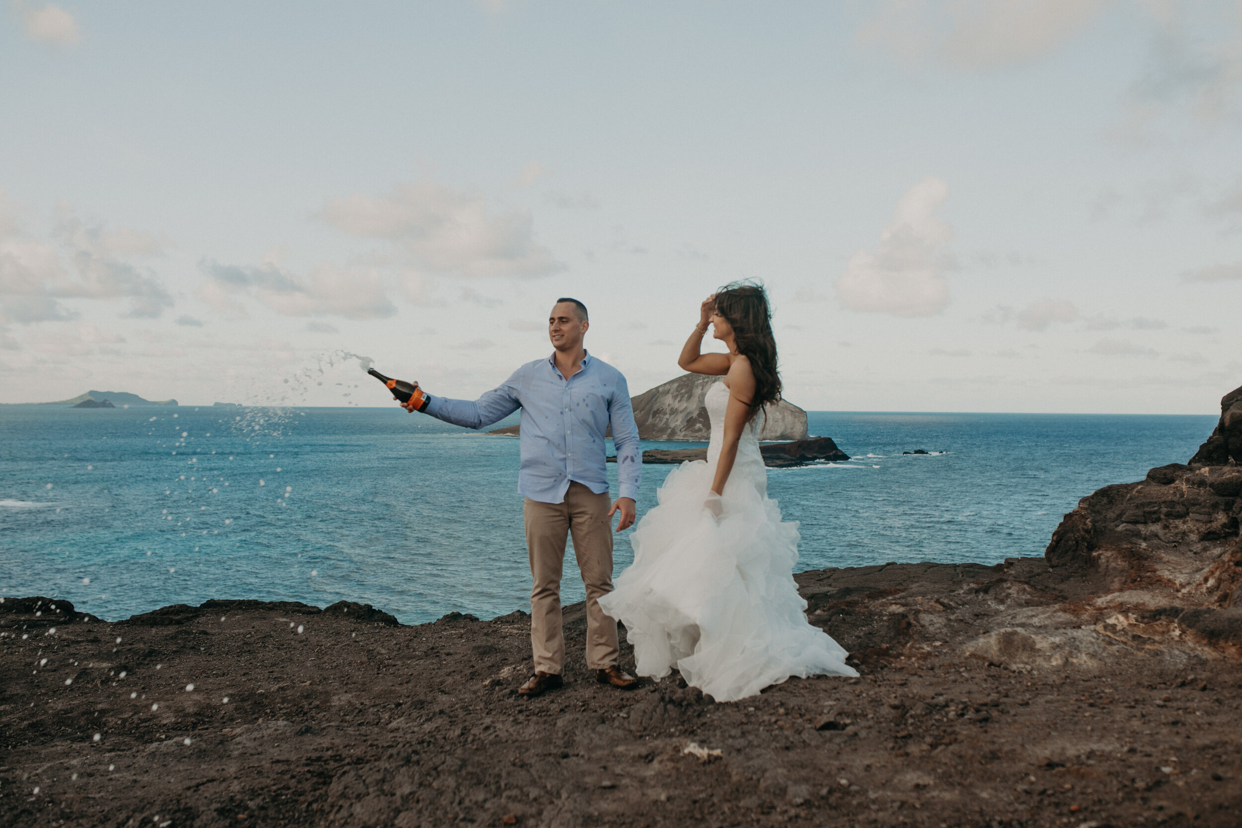  a couple pops Champagne after their elopement at Makapuu Lookout on Oahu Hawaii #elopetohawaii #hawaiielopement #oahuelopement #oahuweddingphotographer #weddingdestinations #hawaiiweddingphotographer #hawaiielopementphotographer #makapuulookout #mak