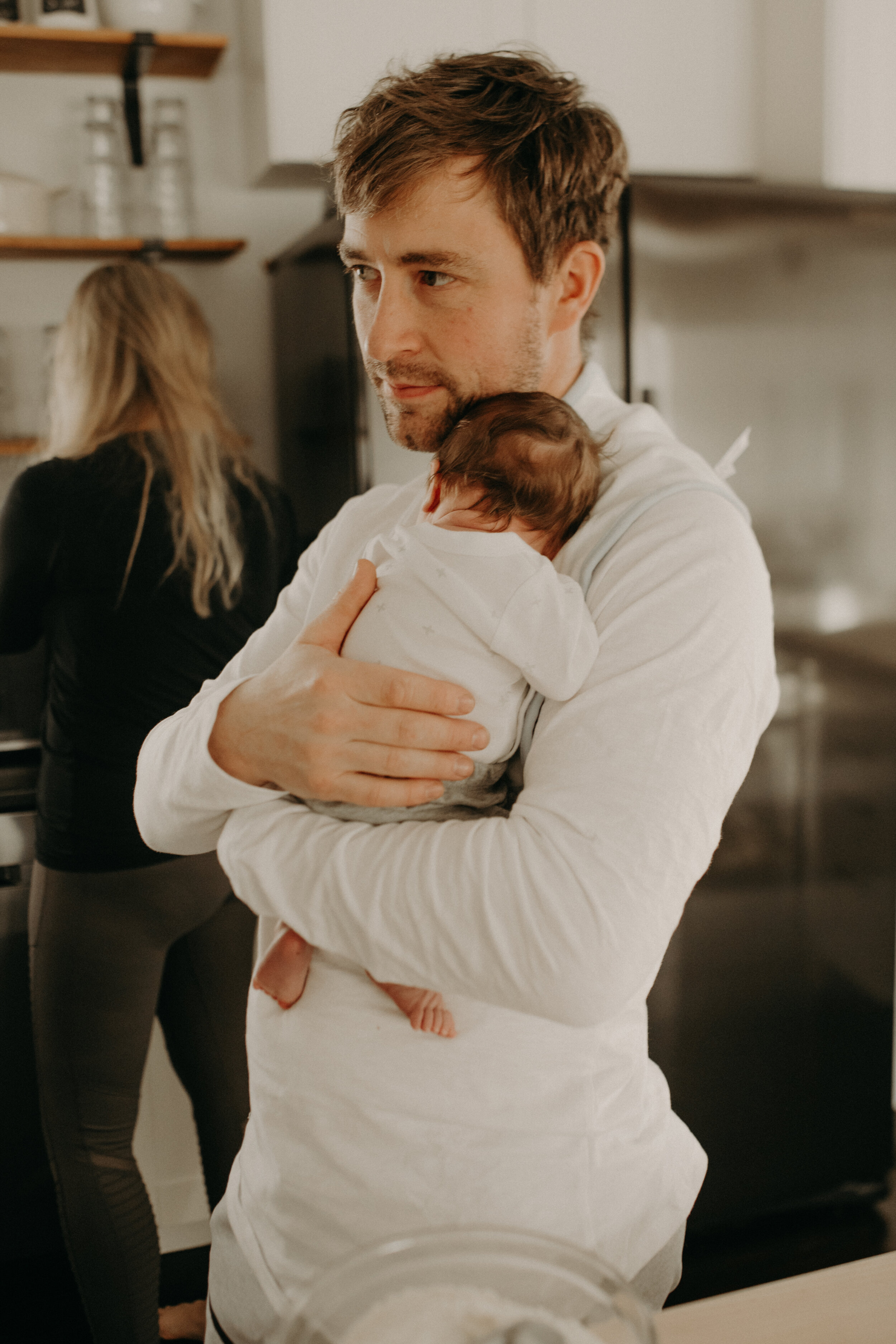  River Falls Family. River Falls Wisconsin. Mother cooking in the kitchen. Lifestyle Newborn Photo session. Wisconsin Newborn Photographer. Wisconsin Lifestyle Newborn Photographer. Lifestyle Newborn In Home Session. Beautiful mom in white making cho