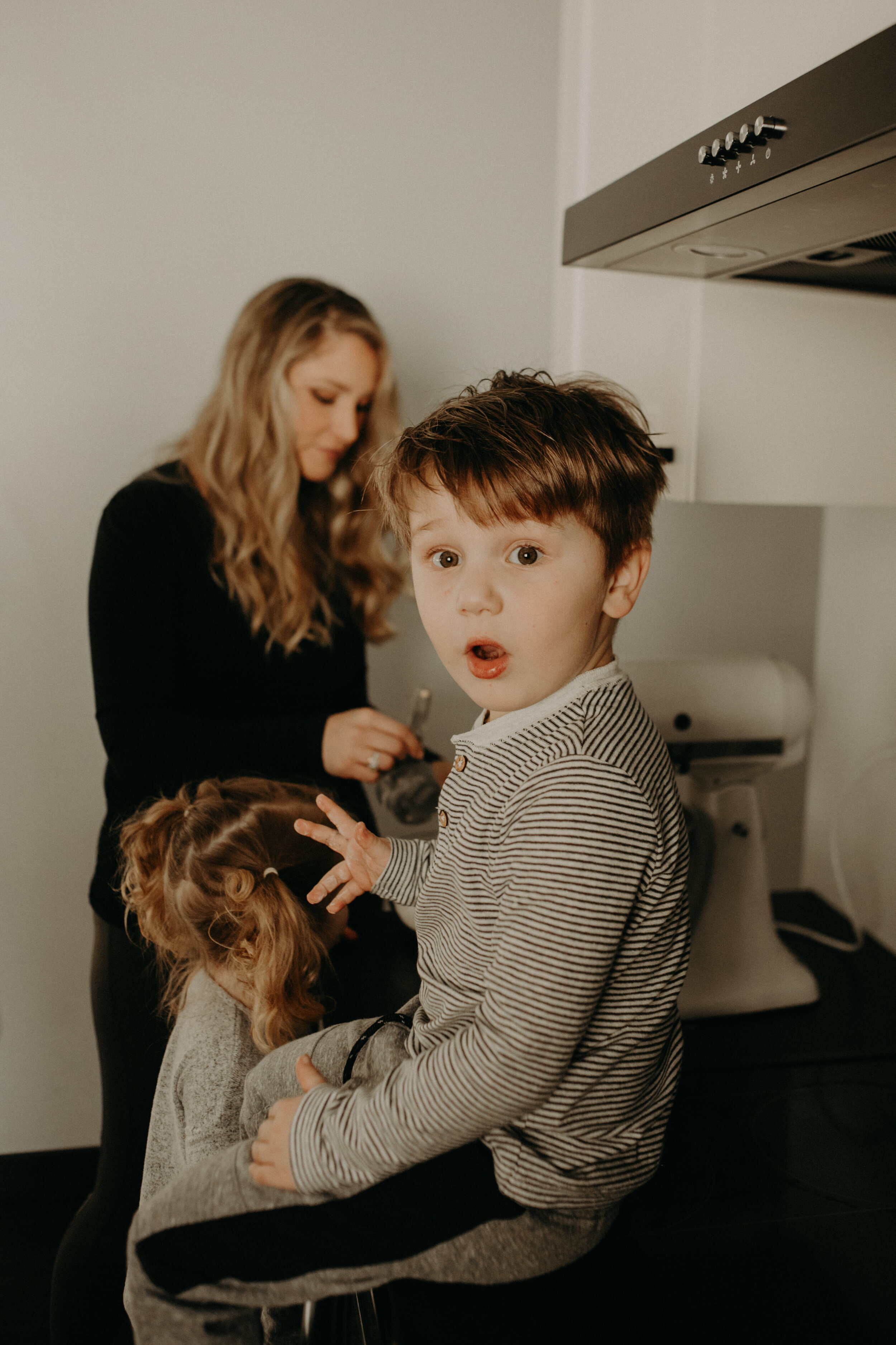  River Falls Family. River Falls Wisconsin. Mother cooking in the kitchen. Lifestyle Newborn Photo session. Wisconsin Newborn Photographer. Wisconsin Lifestyle Newborn Photographer. Lifestyle Newborn In Home Session. Beautiful mom in white making cho