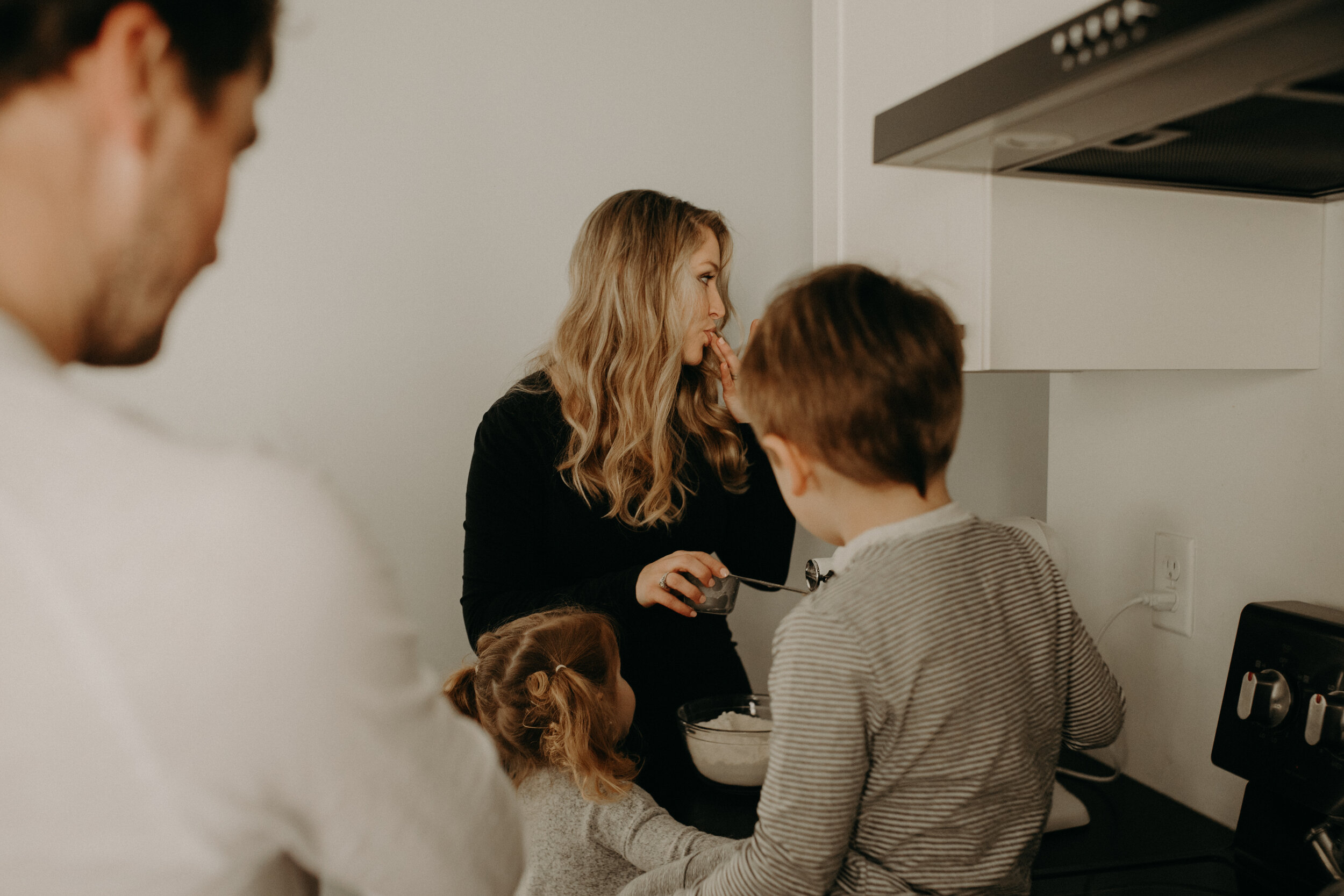  River Falls Family. River Falls Wisconsin. Mother cooking in the kitchen. Lifestyle Newborn Photo session. Wisconsin Newborn Photographer. Wisconsin Lifestyle Newborn Photographer. Lifestyle Newborn In Home Session. Beautiful mom in white making cho