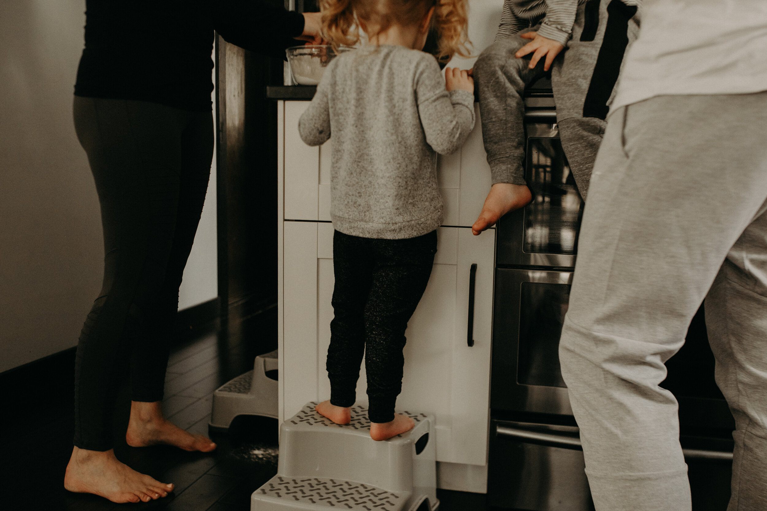  River Falls Family. River Falls Wisconsin. Mother cooking in the kitchen. Lifestyle Newborn Photo session. Wisconsin Newborn Photographer. Wisconsin Lifestyle Newborn Photographer. Lifestyle Newborn In Home Session. Beautiful mom in white making cho