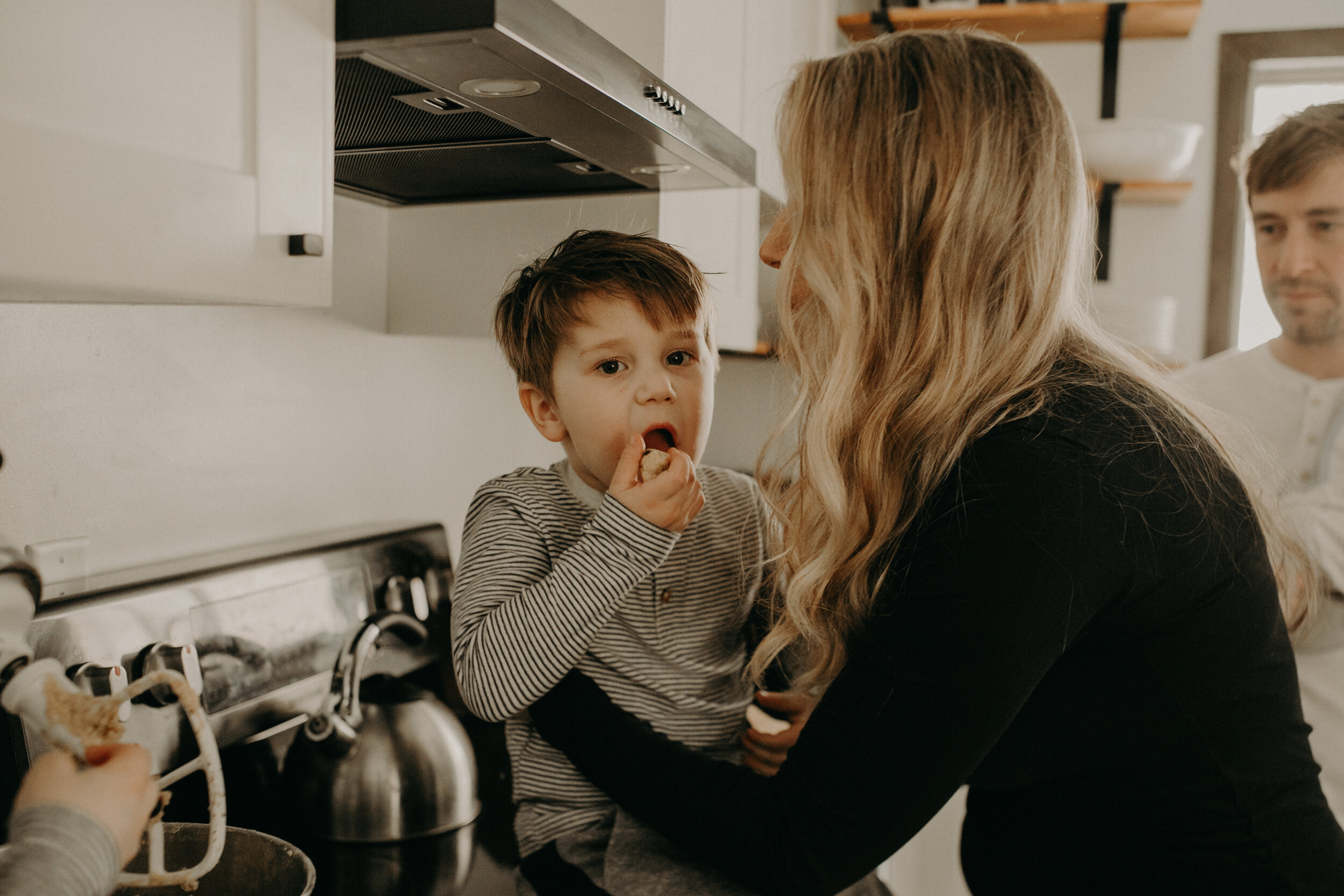  River Falls Family. River Falls Wisconsin. Mother cooking in the kitchen. Lifestyle Newborn Photo session. Wisconsin Newborn Photographer. Wisconsin Lifestyle Newborn Photographer. Lifestyle Newborn In Home Session. Beautiful mom in white making cho