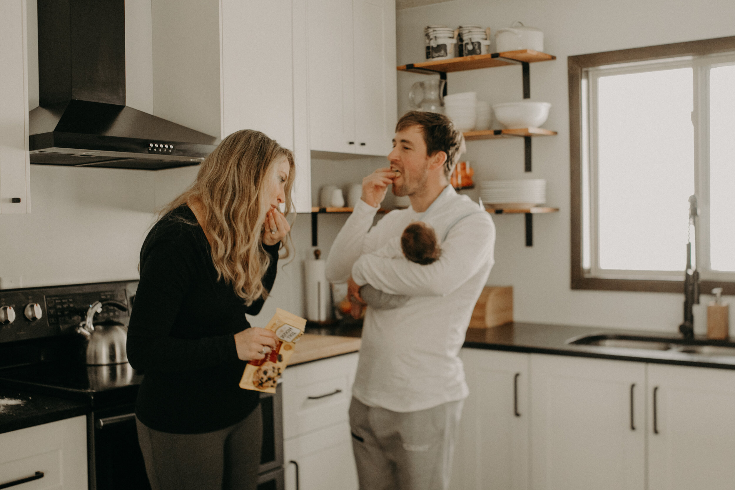  River Falls Family. River Falls Wisconsin. Mother cooking in the kitchen. Lifestyle Newborn Photo session. Wisconsin Newborn Photographer. Wisconsin Lifestyle Newborn Photographer. Lifestyle Newborn In Home Session. Beautiful mom in white making cho