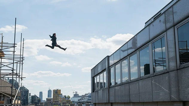 Ethan Hunt (Tom Cruise) leaps buildings in an urban chase sequence in Mission: Impossible - Fallout . Cruise broke an ankle during the shoot, delaying production by eight weeks.
