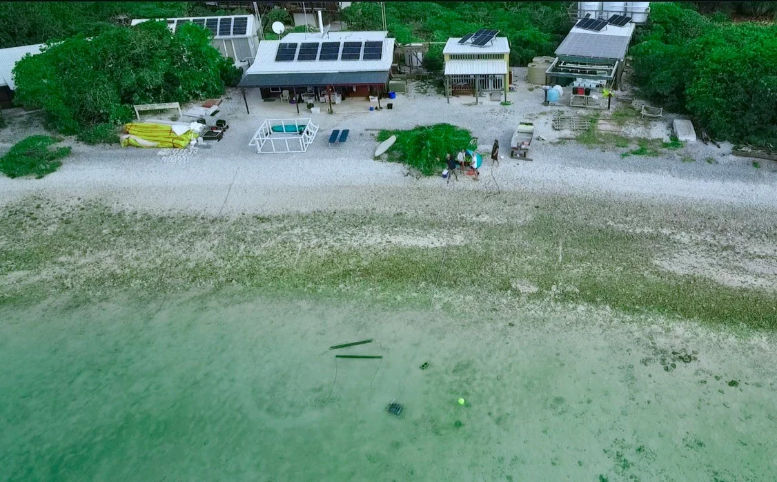 Aerial view of time series station and Barefoot Biogeochemistry researchers to investigate groundwater effluent to lagoon. Left to right: a dancing Isaac Santos and laughing onlookers Kay Davis, James Archibald, Ashly McMahon.