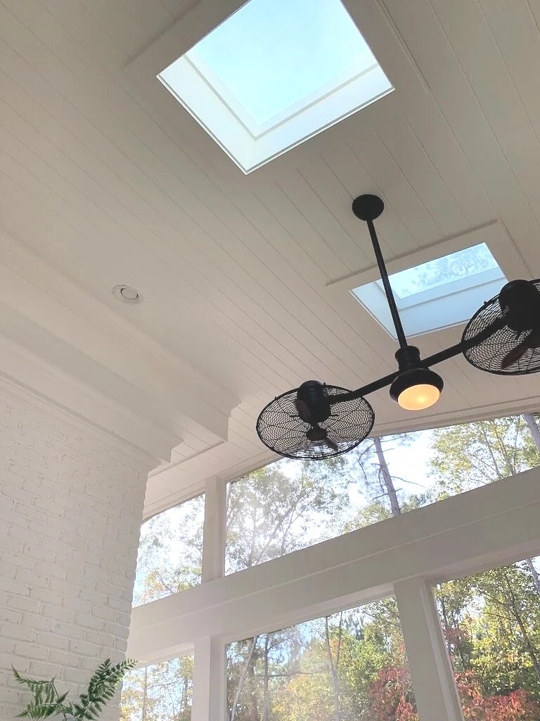 Farmhouse style screened in porch featuring white painted brick, shiplap ceiling and fun double ceiling fan.