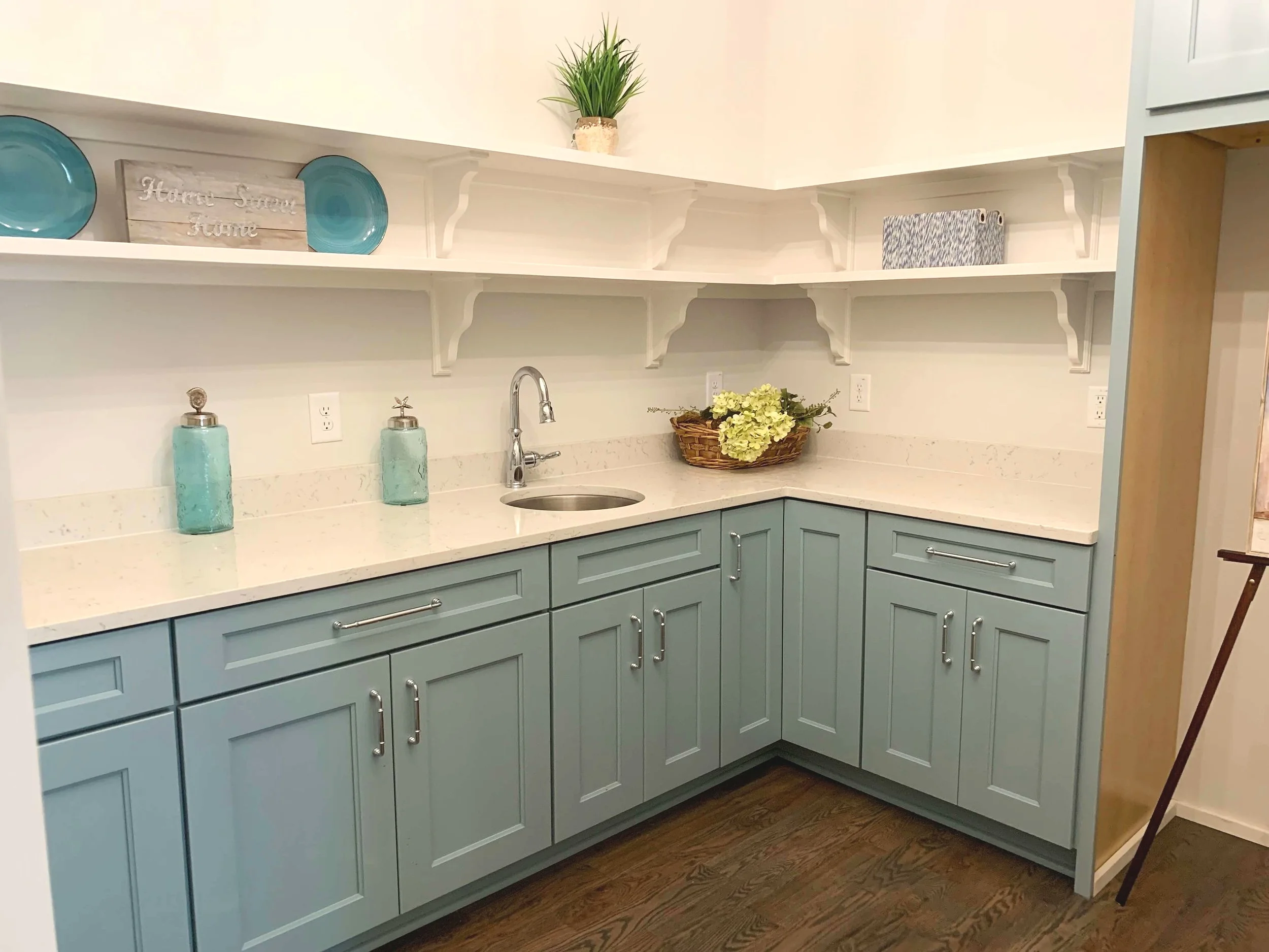 Kitchen butler’s pantry with blue cabinets, open shelving, quartz counters and bar sink.