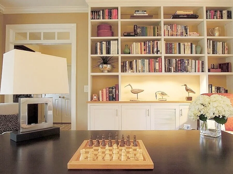 Custom shelving with LED accent lighting displays a collection of carved wood shore birds and keeps favorite books organized.