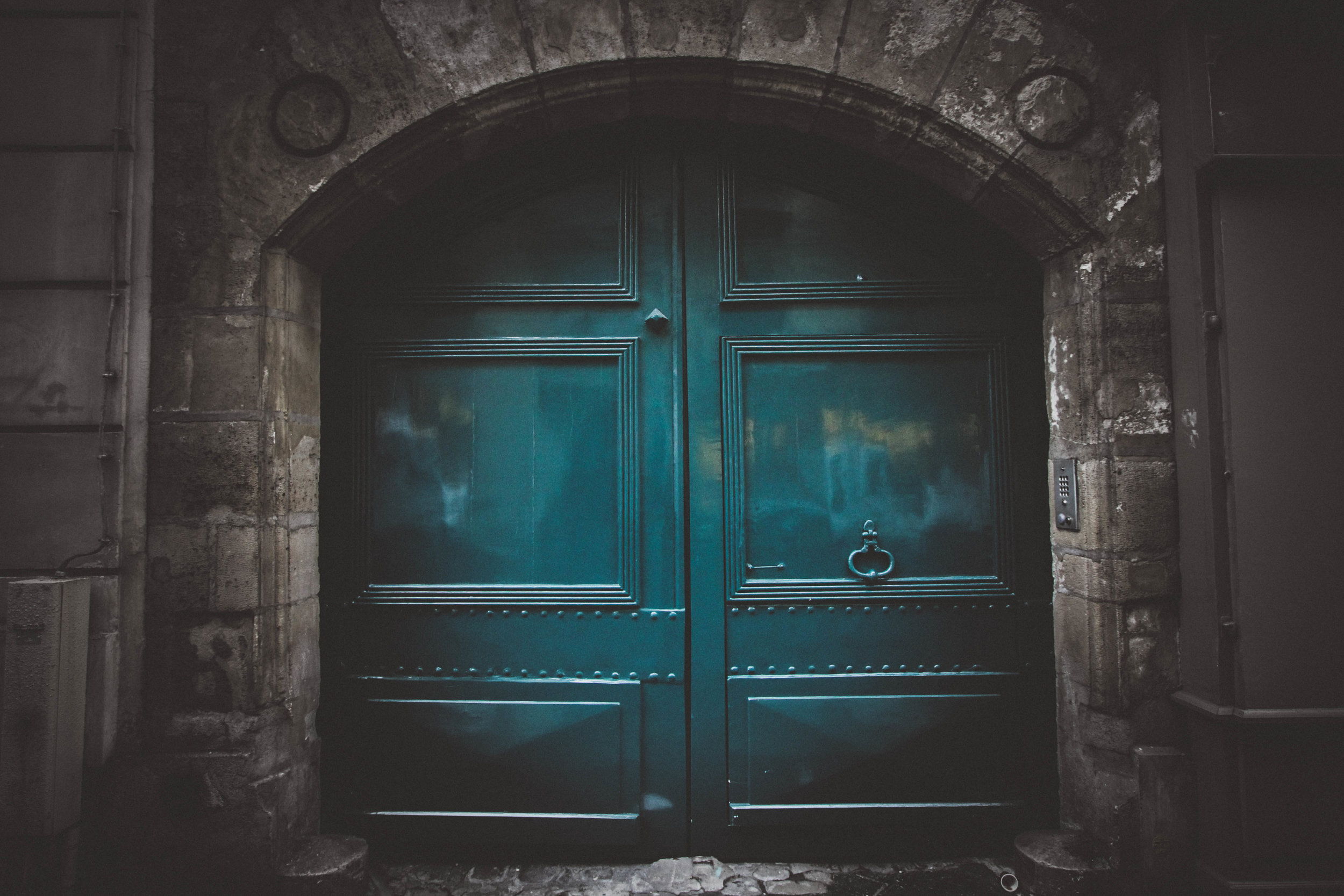 Teal double door with gray stone blocks surrounding.