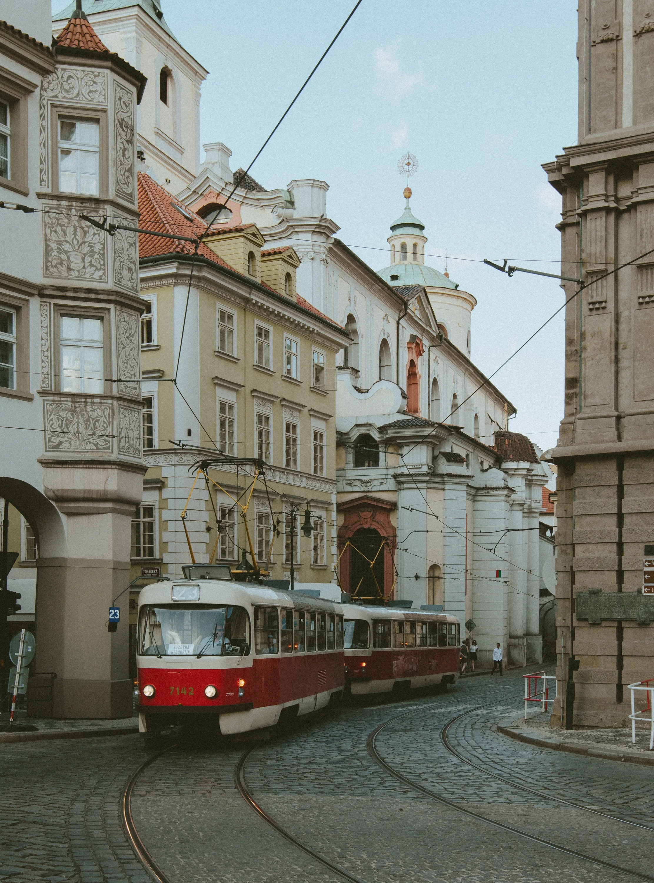 A red and white trolley rides through a cobblestone street in Prague. @Jeffrey Czum