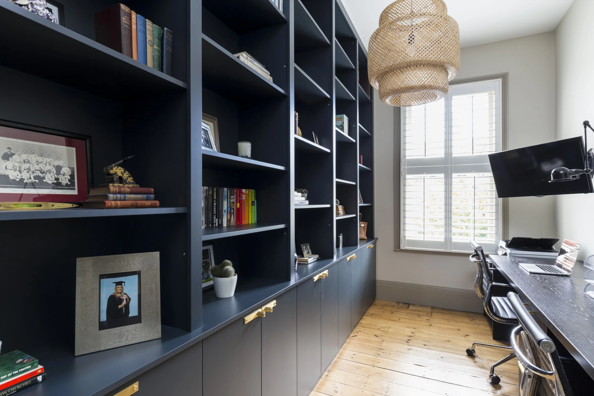Majestic, full height bookcases provide ample storage in this elegant home office. Matt spray painted cabinetry, colour matched to farrow & ball’s ‘railings', creates a moody vibe and the bespoke wenge desk makes the most of the long narrow space incorporating shelves for the printer, filing cabinets as well as space for two to work. Eye catching details such as the buster and punch brass knobs and drawer pulls add interest to the doors and drawers