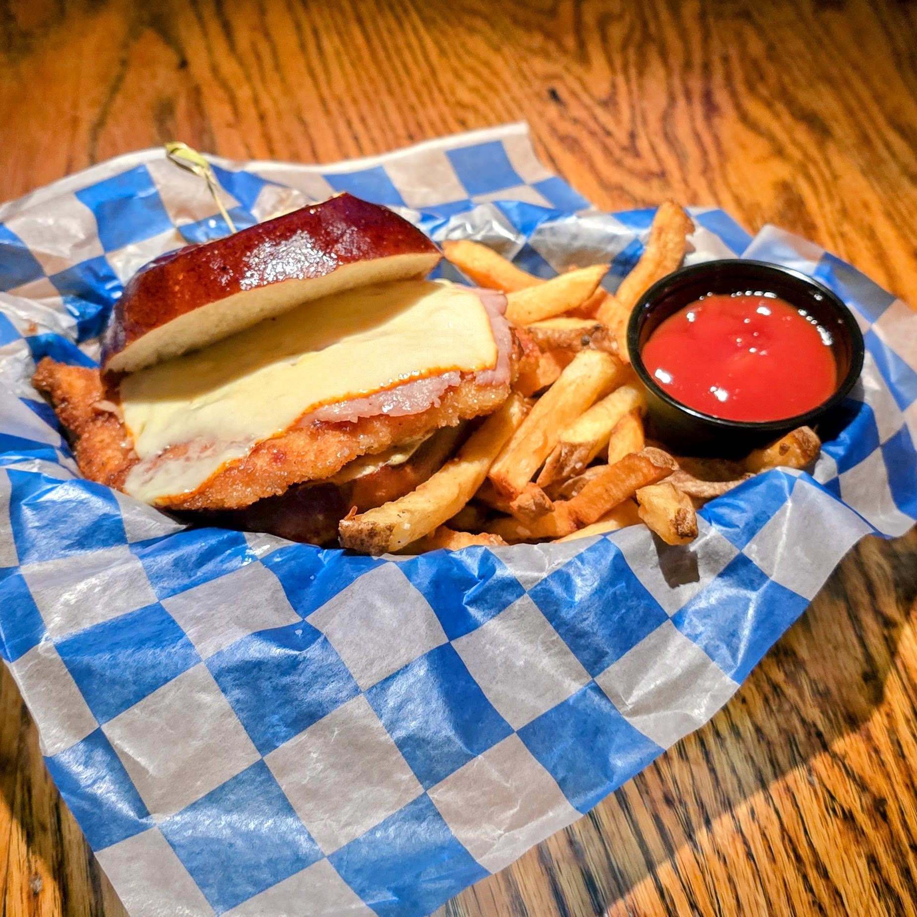 Chicken Schnitzel on a toasted pretzel bun, black forest ham, muenster cheese, served with frites.