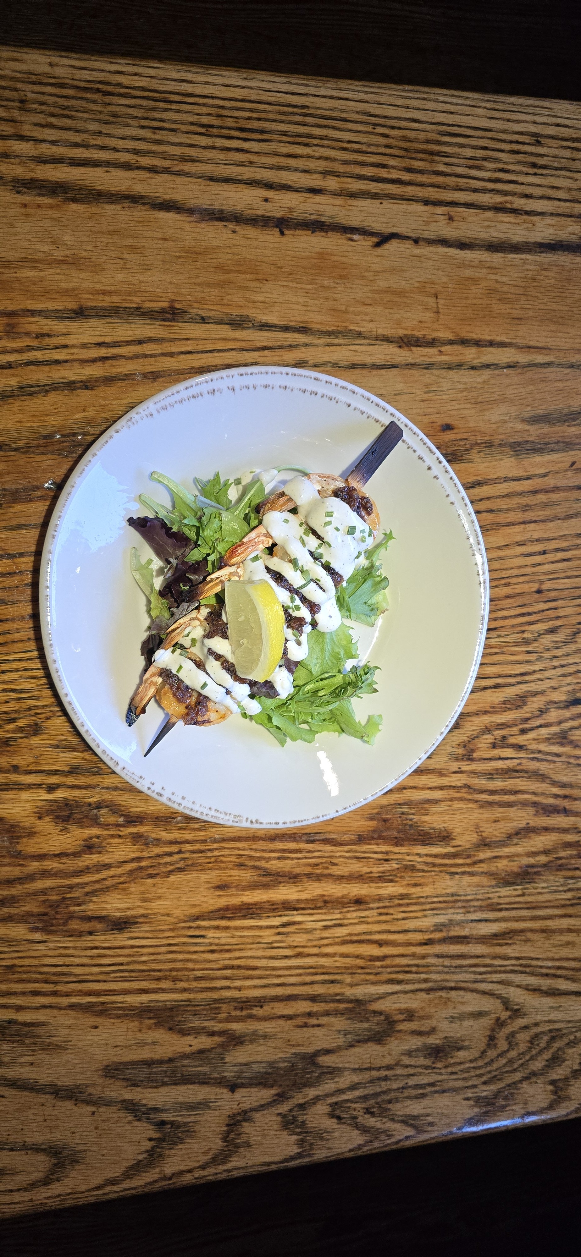 Citrus shrimp skewer with garlic aioli and bacon dressing.