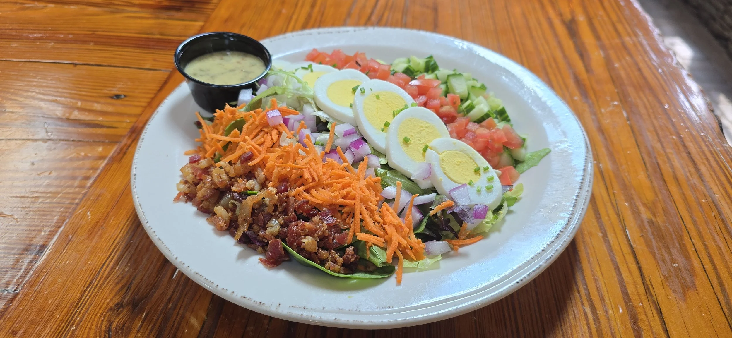 Cobb Salad with egg, corn, tomatoes, bacon, red onion, cumber, and mustard vinaigrette.