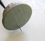 step 7 - Run the needle tool through the beads and out the bottom of the disks to create a hole for the black cage wire. With your fingers roll a 1” long, thin log with black clay to act as the bird’s perch. Bake all the pieces on a foil lined sheet in a 275 degree oven for 30 minutes. Allow to cool completely.