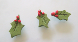 step 8 - Roll out green and red clay. Use a craft knife to cut holly leaf shapes in the green clay and create veins in the center. Roll bits of red clay in your fingers to create the berries. Press them to the leaves. Use an Etch n’ Pearl tool to make a holehidden in the berries which will allow you to connect wire for hanging them. Bake the leaves on a foil lined sheet in a 275 degree oven for 30minutes. Allow to cool before handling.