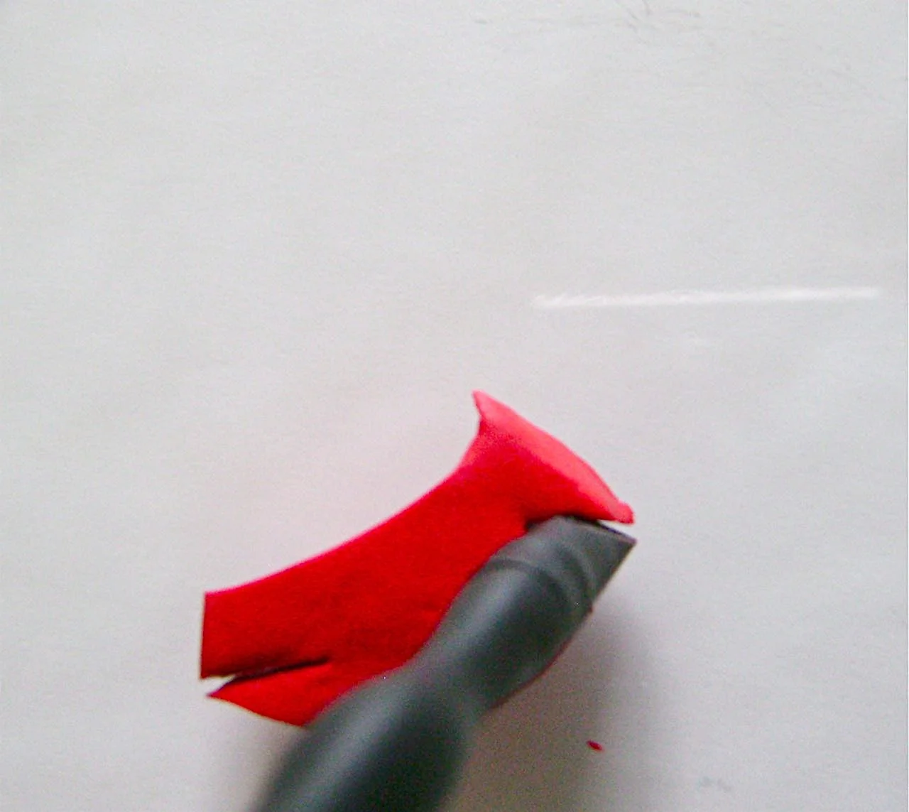 step 3 - Use the flat edge of the sculpting tool to lift the clay up from the slit to create the bird’s head.