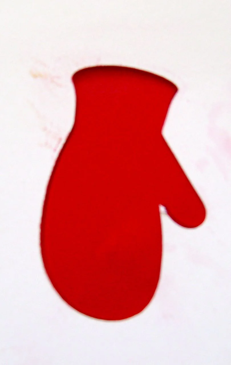 step 1 - Condition and roll out the clay to about 1/8". Print and cut out mitten stencil. Lay the stencil over the clay and roll across it to transfer the stencil outline.