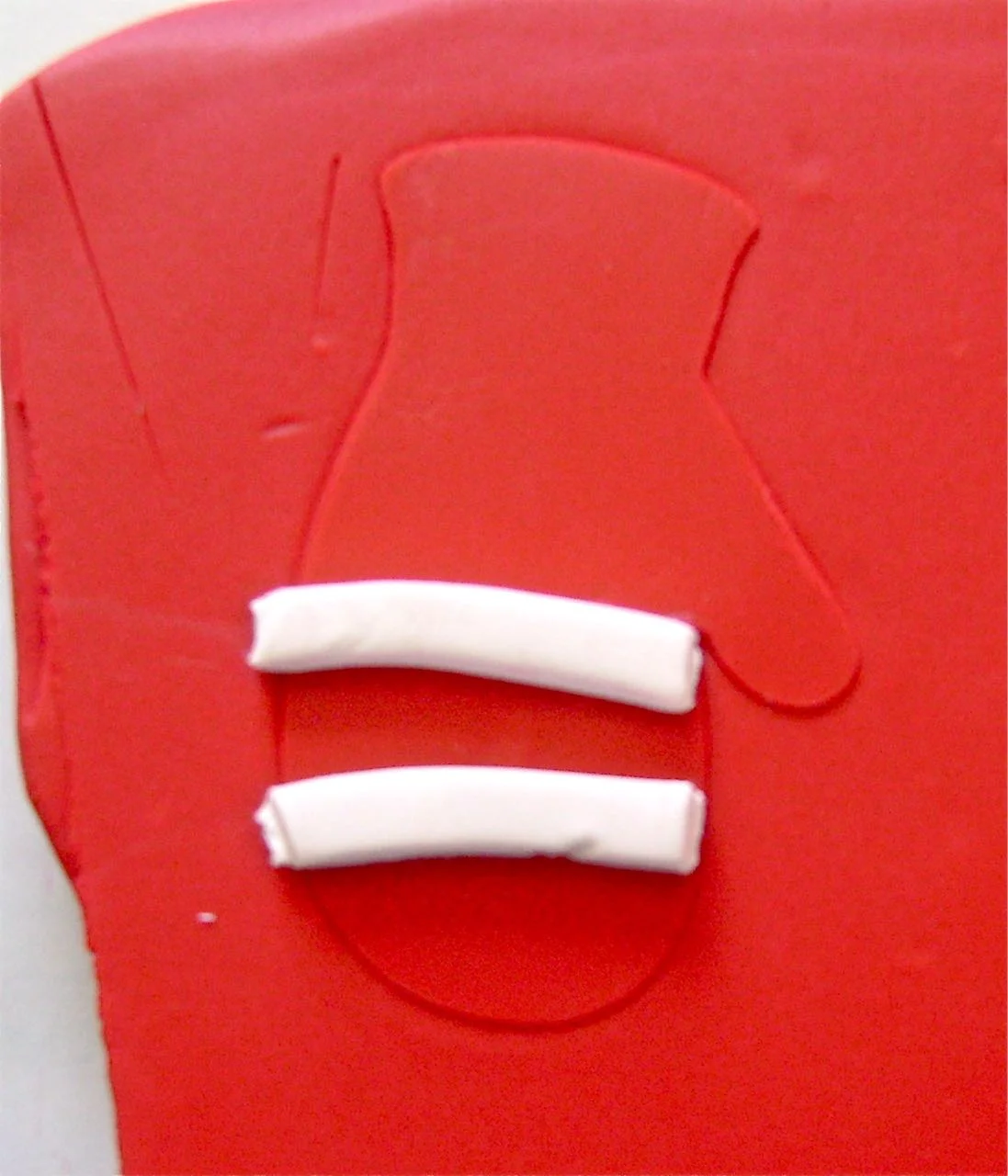 step 2 - Roll out two small pieces for stripes on the mittens. Cut them to equal sizes and position them on the clay.