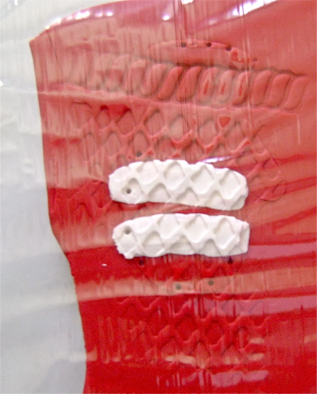 step 5 - If the mitten outline has been slightly faded by the texturing, replace the stencil on the clay and use a tooth pick to make small holes following the outline. Place kitchen plastic wrap over the clay. Use a craft knife to cut out the mitten.