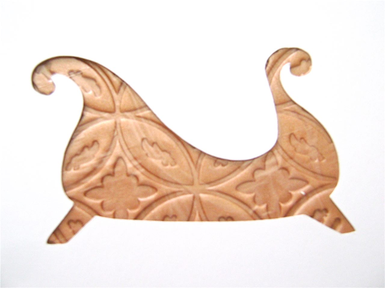 step 3 - Place a piece of plastic wrap on the clay. Position the sleigh stencil over the plastic. Use the stencil as a guide for cutting the clay with a craft knife.