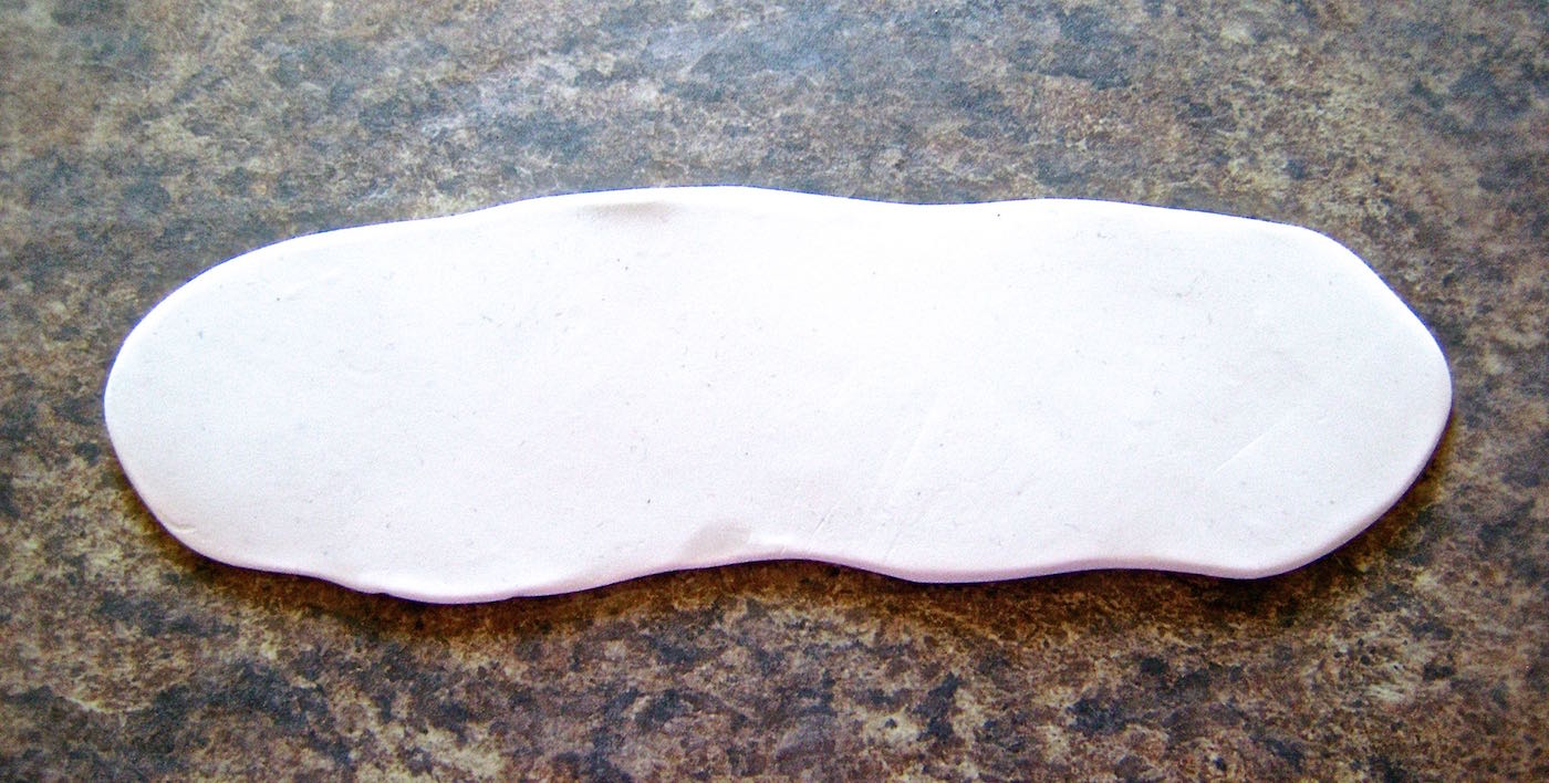 step 1 - Condition the clay by kneading it until it is soft and pliable. Cover the work surface and the clay with wax paper. Using a roller, flatten the clay to measure 1.5” wide and slightly longer than the size of your wrist. The thickness of the clay should be no less than 1/8 inch.