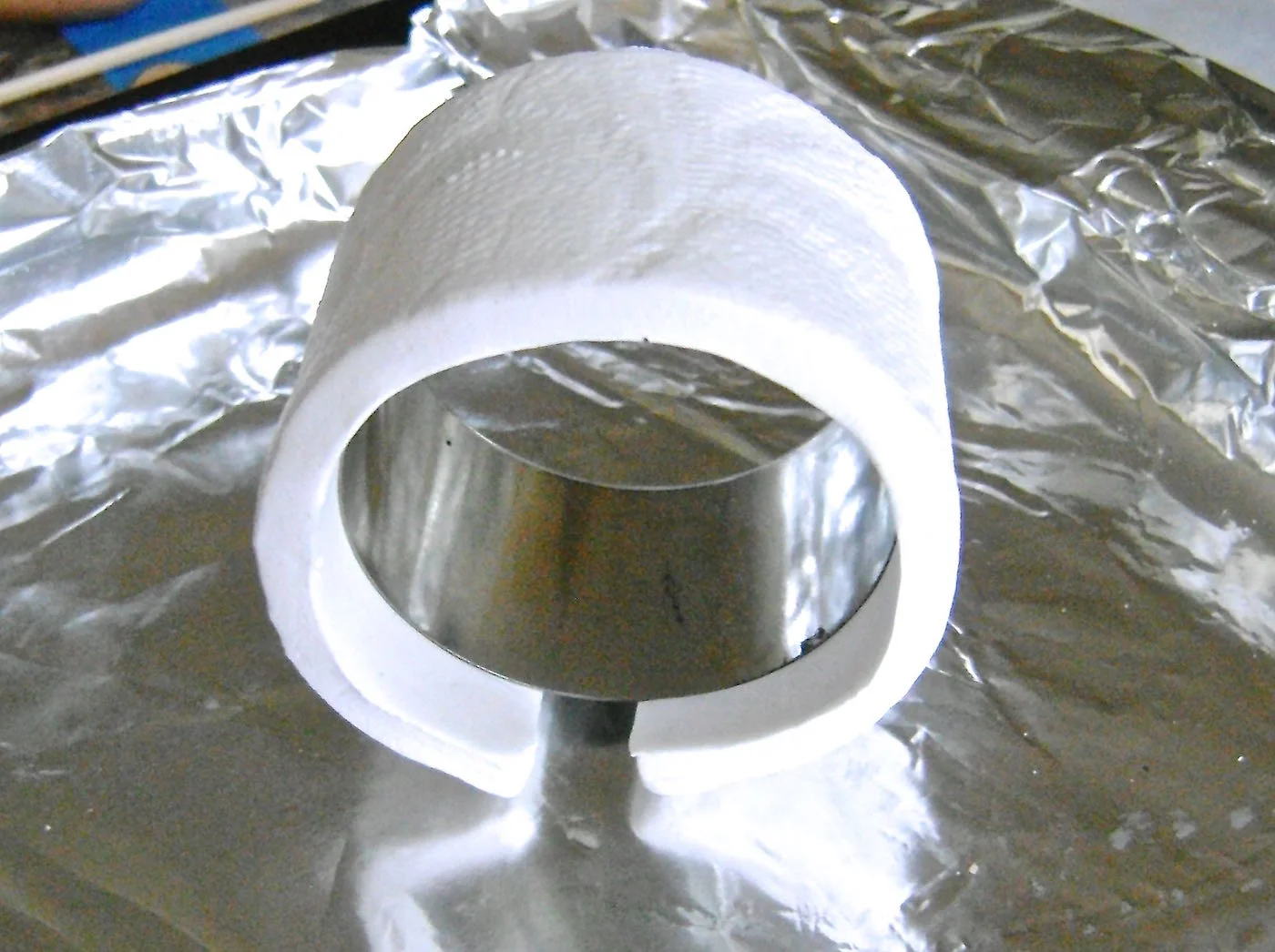 step 6 - Wrap the clay around an appropriate size metal cookie cutter. Ideally, when the clay is wrapped, there should be a space between the two ends of about .75”. The size cookie cutter to use will be determined by your wrist size. Bake the clay on a parchment covered baking sheet in a 275 degree oven for 15 minutes. Let cool completely before separating the clay from the cookie cutter. A finger nail file or sanding paper will easily smooth out any rough clay edges.