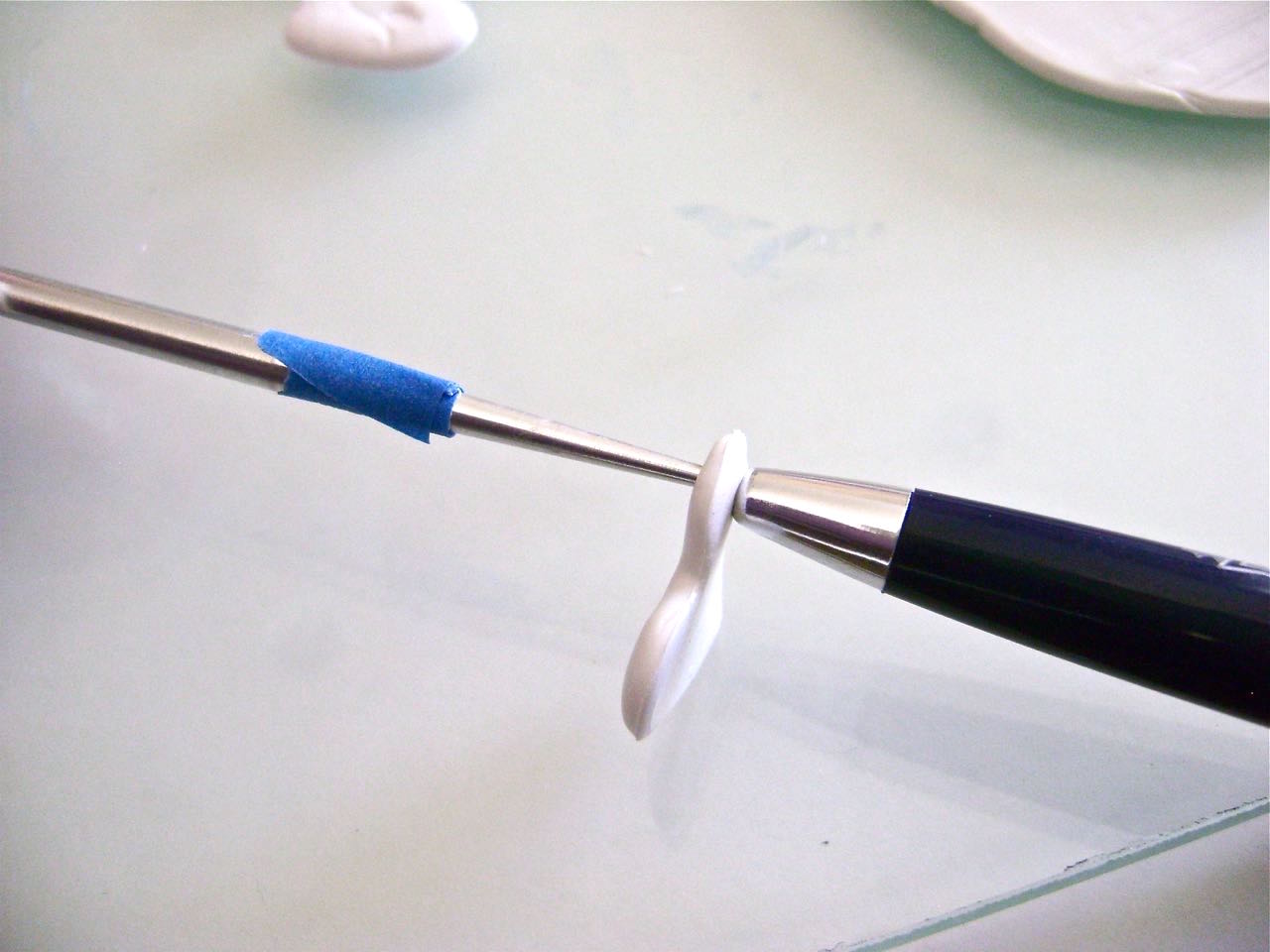 step 7 - Here’s another tip using an old ballpoint pen. Put the tip of the Etch ‘n Pearl tool into the front surface of the clay. On the back side line up the hole of the ball point pen then gently twist the tool through the clay and into the pen hole. This creates an extremely clean hole on both the front and the back side of the heart.