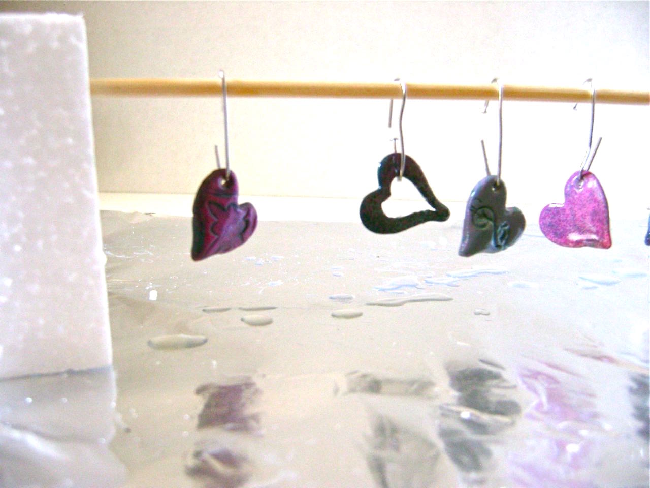 step 12 - Shape small hangers for the hearts and frames with paper clips. Dip each heart in a small container of Diamond Glaze. Tap off excess and hang the pieces to dry on a wood pick. Protect the surface beneath. After about a half hour you’ll see a bubble of glaze hanging off each piece. Remove it by running your finger smoothly against it. Allow the pieces to dry over night.