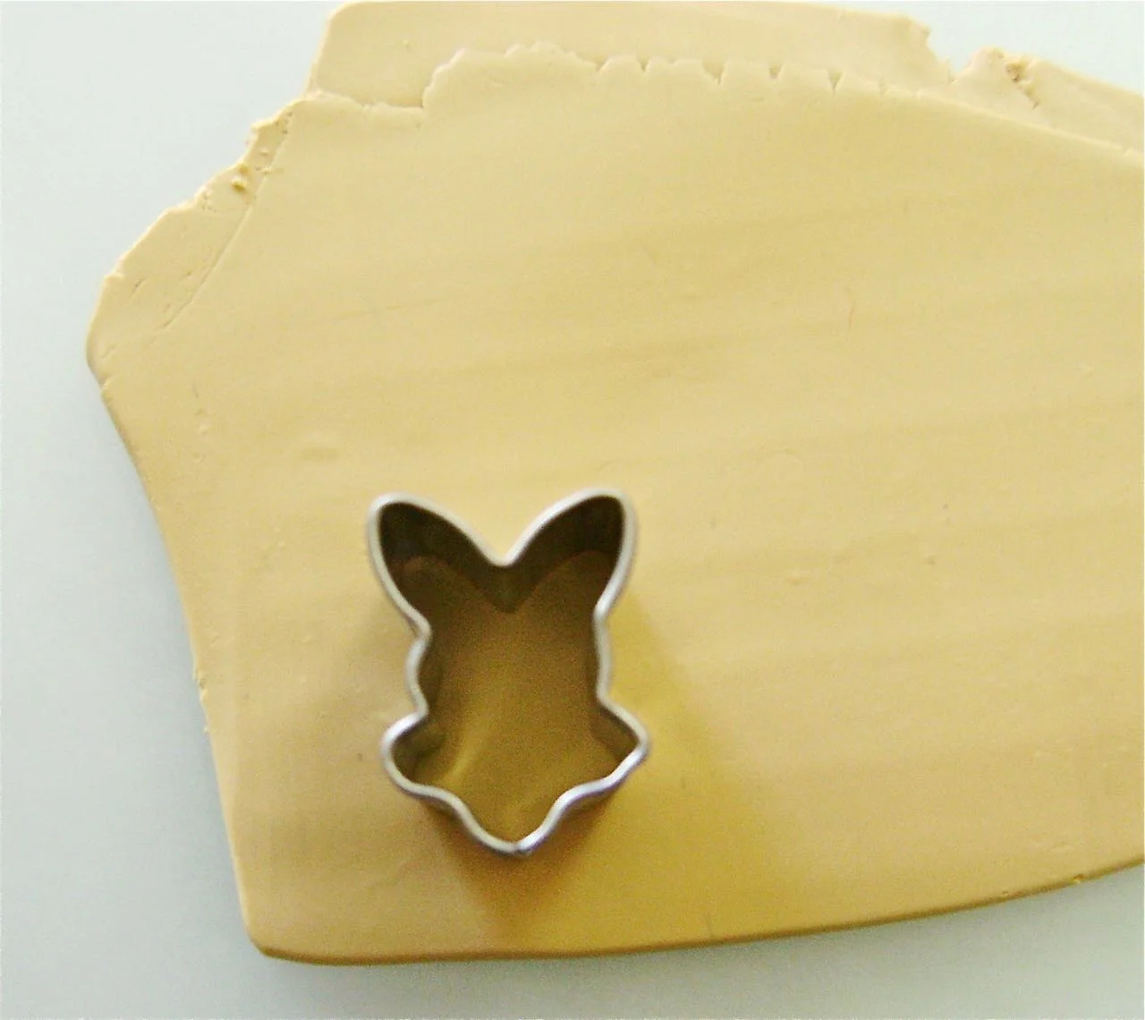 step 5 - Place plastic wrap over the Ecru clay. Using a bunny head cutter, cut two pieces.