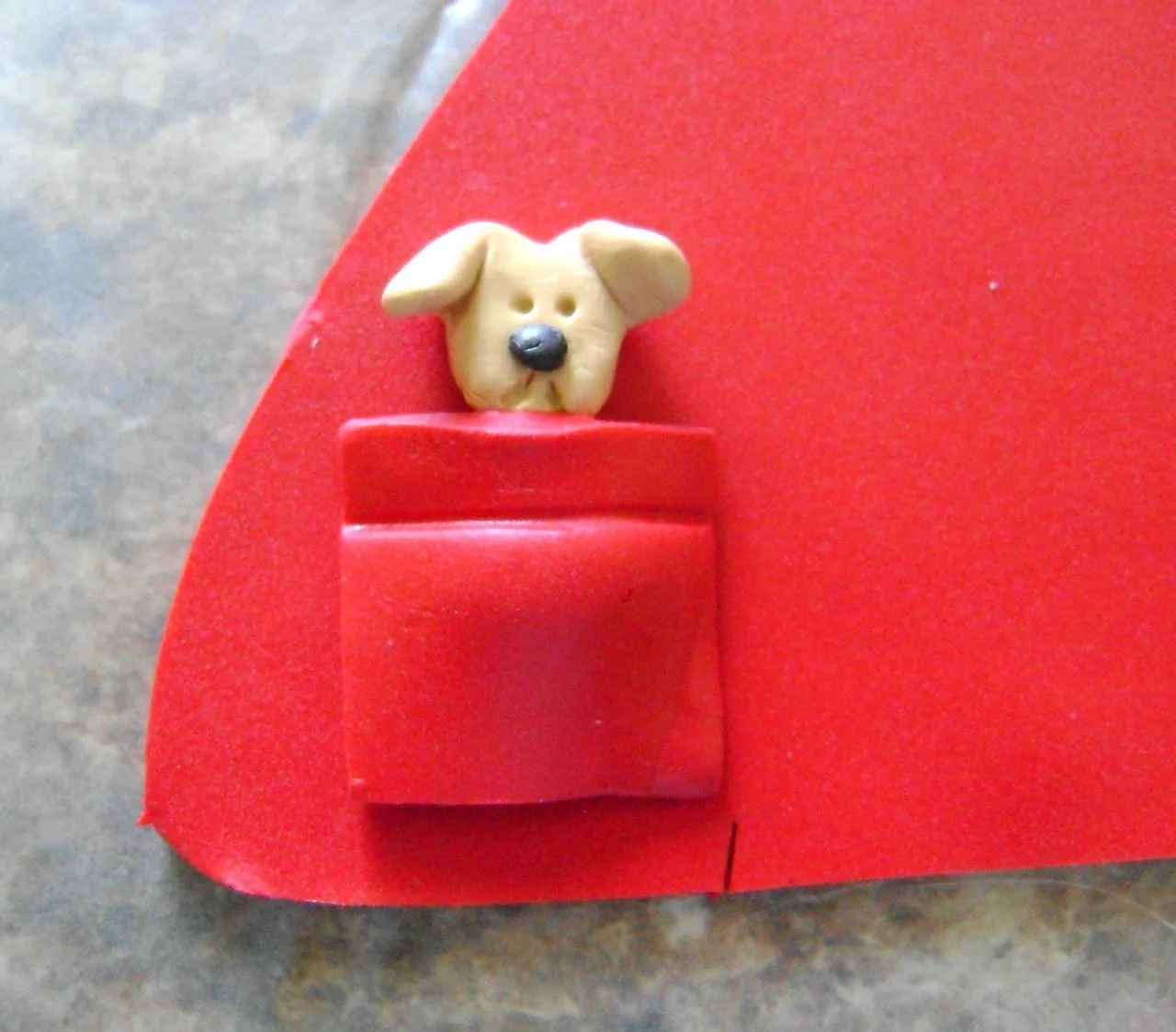 step 11 - Place the dog and pocket close to the side seam gash and about .25” from the bottom edge of the clay on the left side of the coat. Position the other pocket on the right side of the coat. Press the pocket edges to the coat.