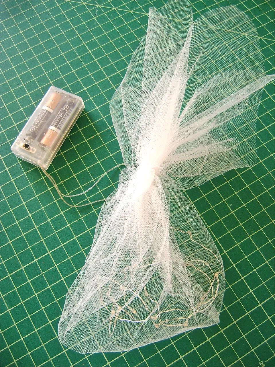 step 17 - Assembly - Put batteries in the light pack. Place the battery pack and the lights in the cone. Slip the cone into the sconce. The light switch should be positioned for easy access. Arrange netting to stick out the top.