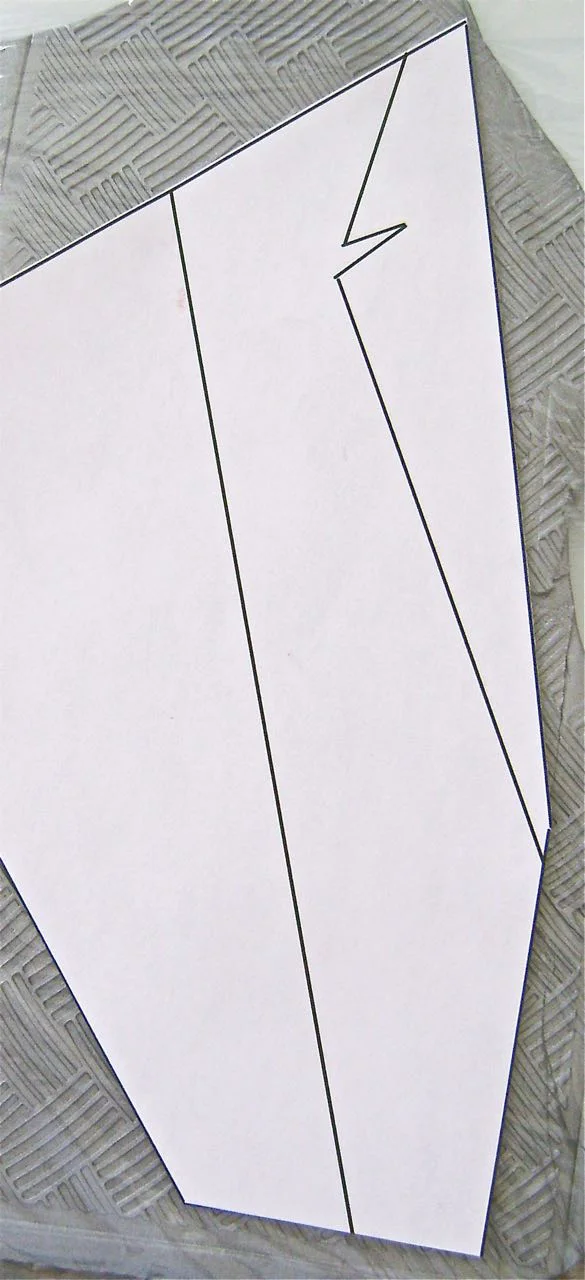 step 10 - Place a piece of plastic wrap over the clay followed by the sconce template. Cut out the sconce shape with a craft knife. Remove the template and the plastic wrap. Reverse the template and cut out the second sconce piece.