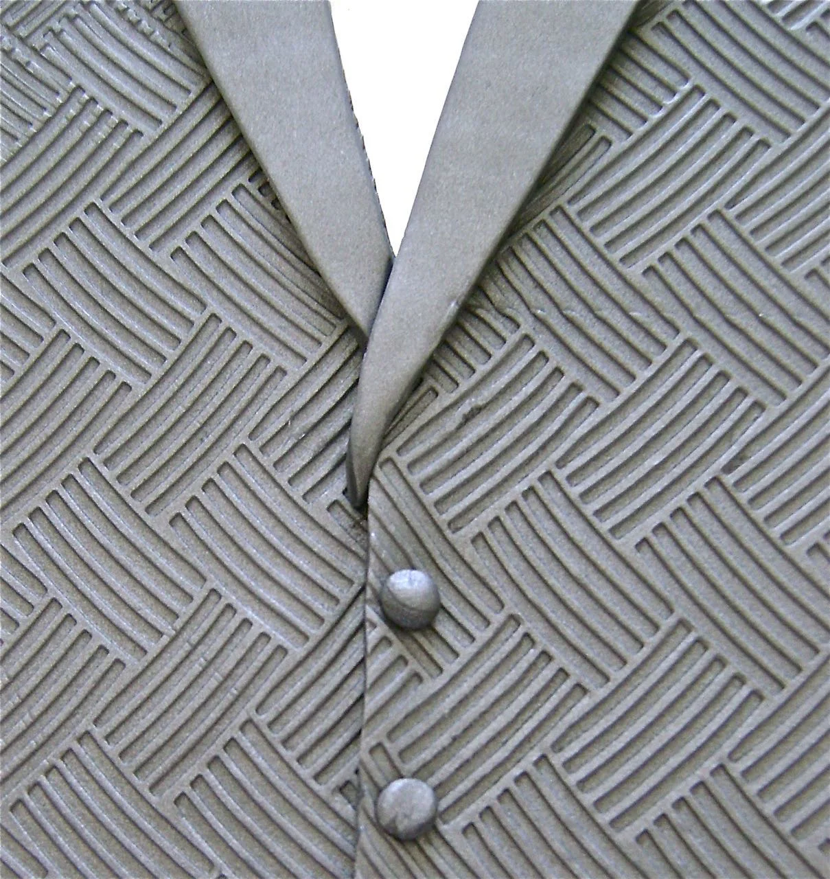 step 13 - Arrange the right lapel onto the sconce first aligning the edges. Curve the pointed bottom slightly into the center. Add the left lapel cutting away excess as it meets the right lapel. Press the lapels to the clay sconce pieces. Roll bits of clay in your palm to create the buttons. Press them onto the sconce.