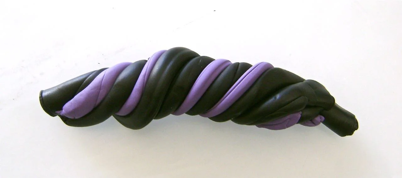 step 1 - Download and print the boot template on copy paper. Roll three strips of black and two strips of plum clay to the same length. Alternate the colors and twist them together. Flatten the piece and run it through the conditioning machine to blend the colors in interesting ways.