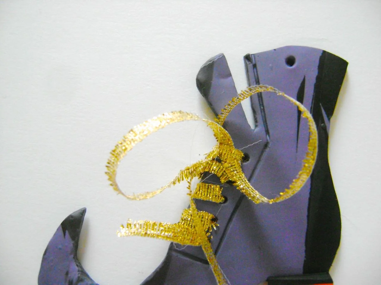 step 8 - Thread the ribbon through all the holes from front to back. Bring the needle under the last wrap until you have a loop. Bring the needle under the wrap again until you have another loop. Tie the two loops together into a knot.