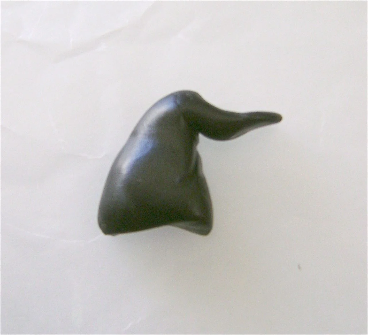 step 7 - Roll a thick piece of black clay into a tube then stretch the end to form the top of the hat. Shape the bottom part into a curve.